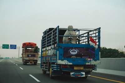 Two trucks driving on a highway under cloudy sky