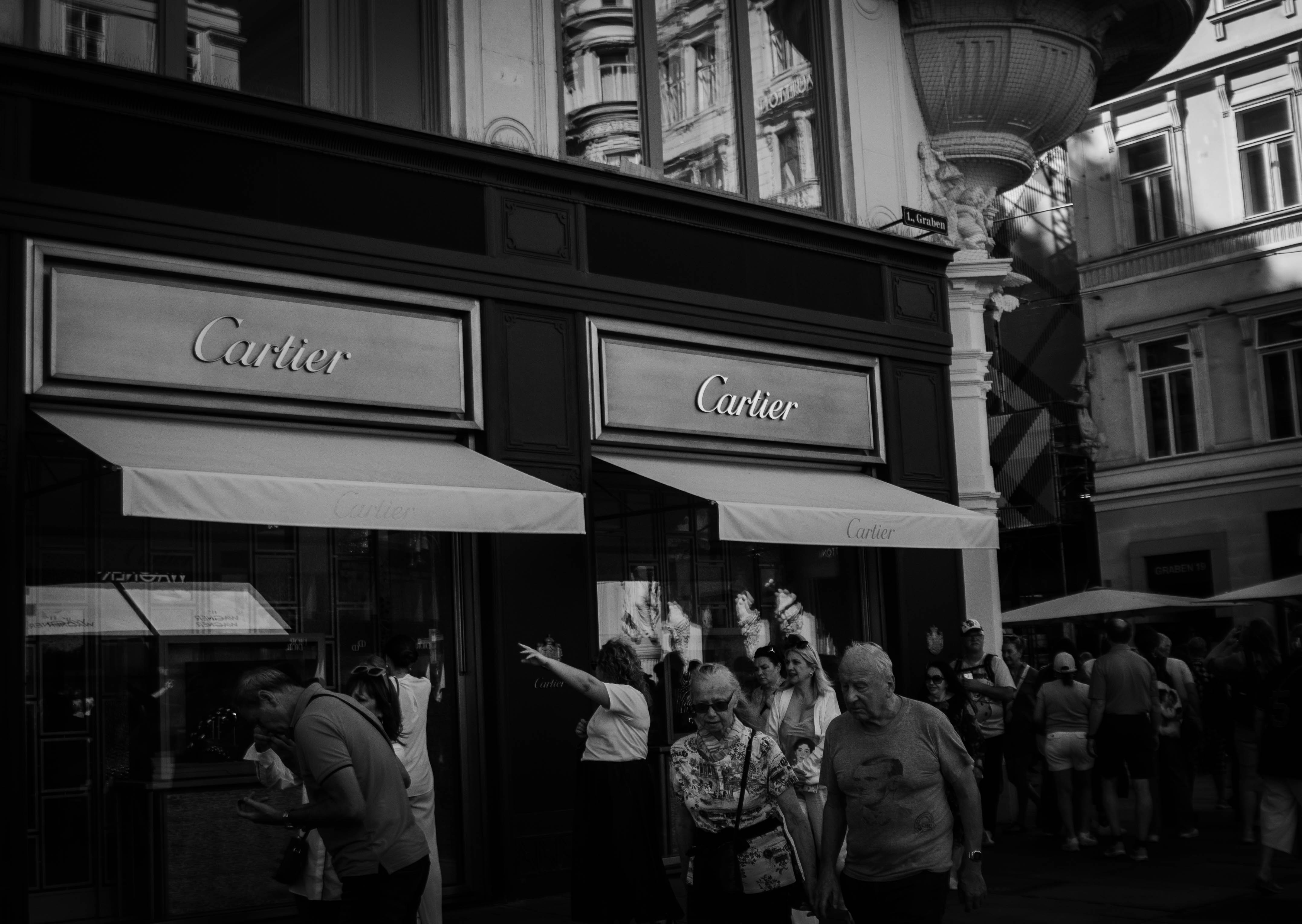 People walk past a cartier store on a sunny day.
