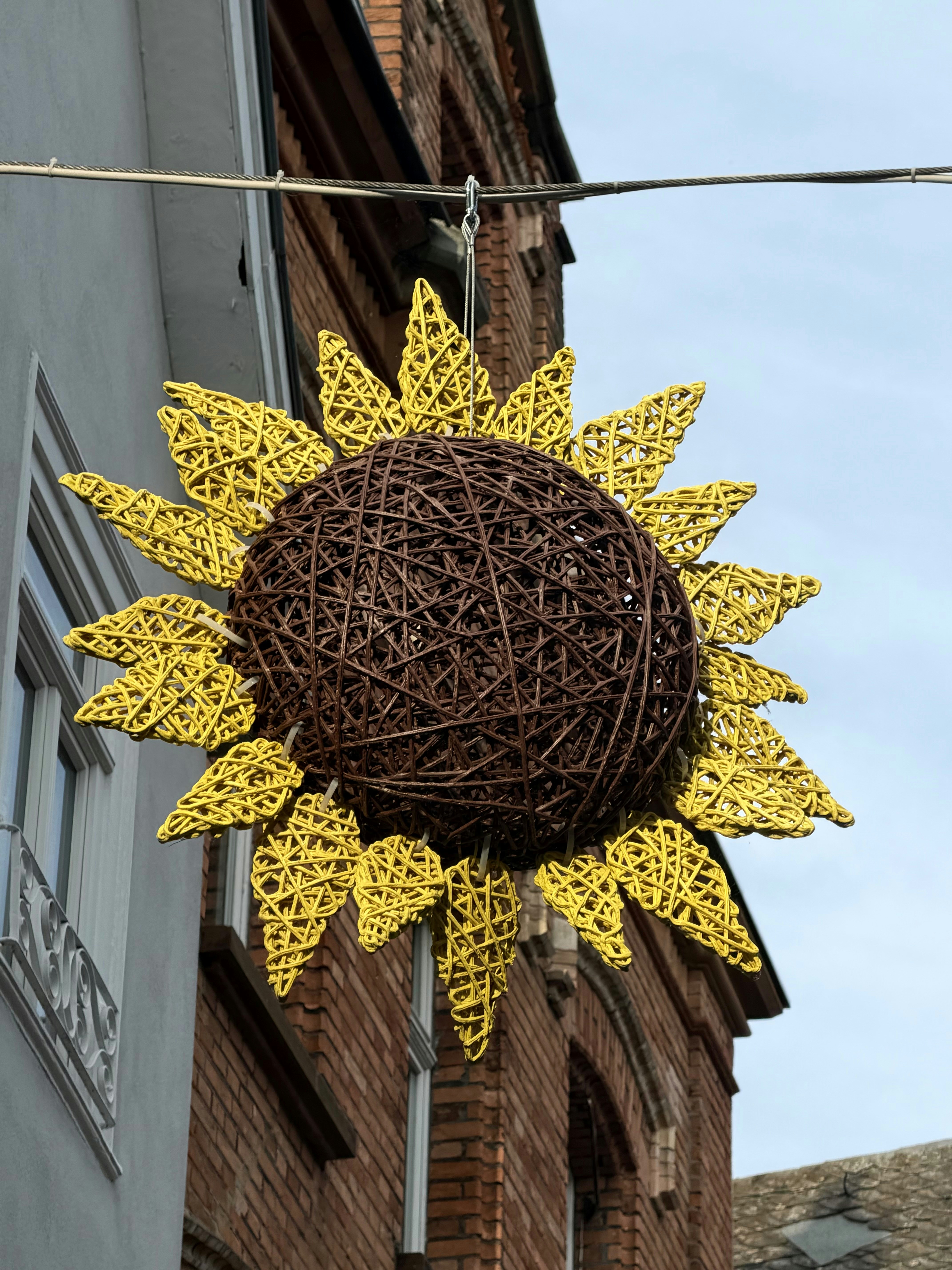 Eine gewebte Sonnenblumendekoration hängt im Freien.