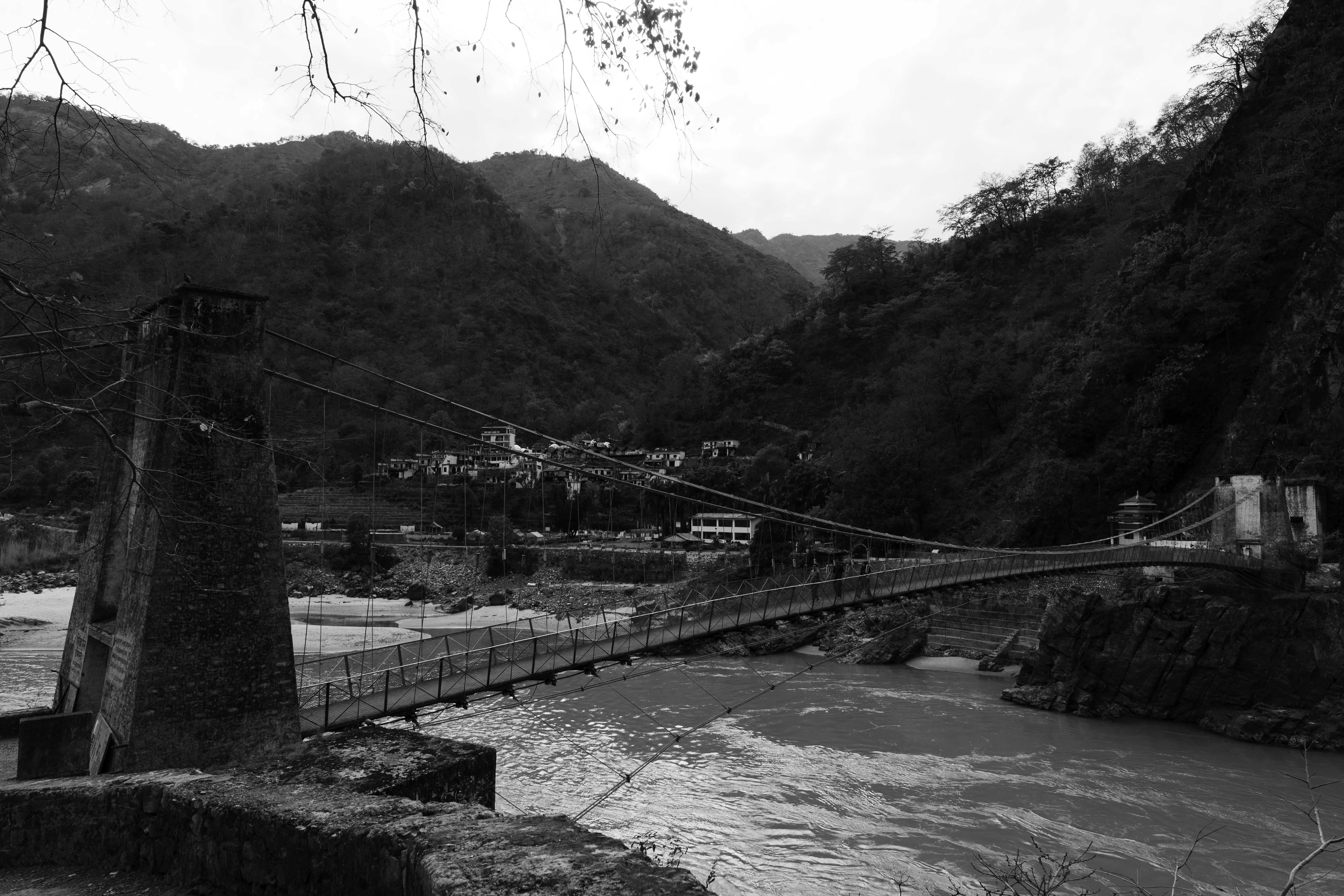 Suspension bridge over a river in a mountainous area.