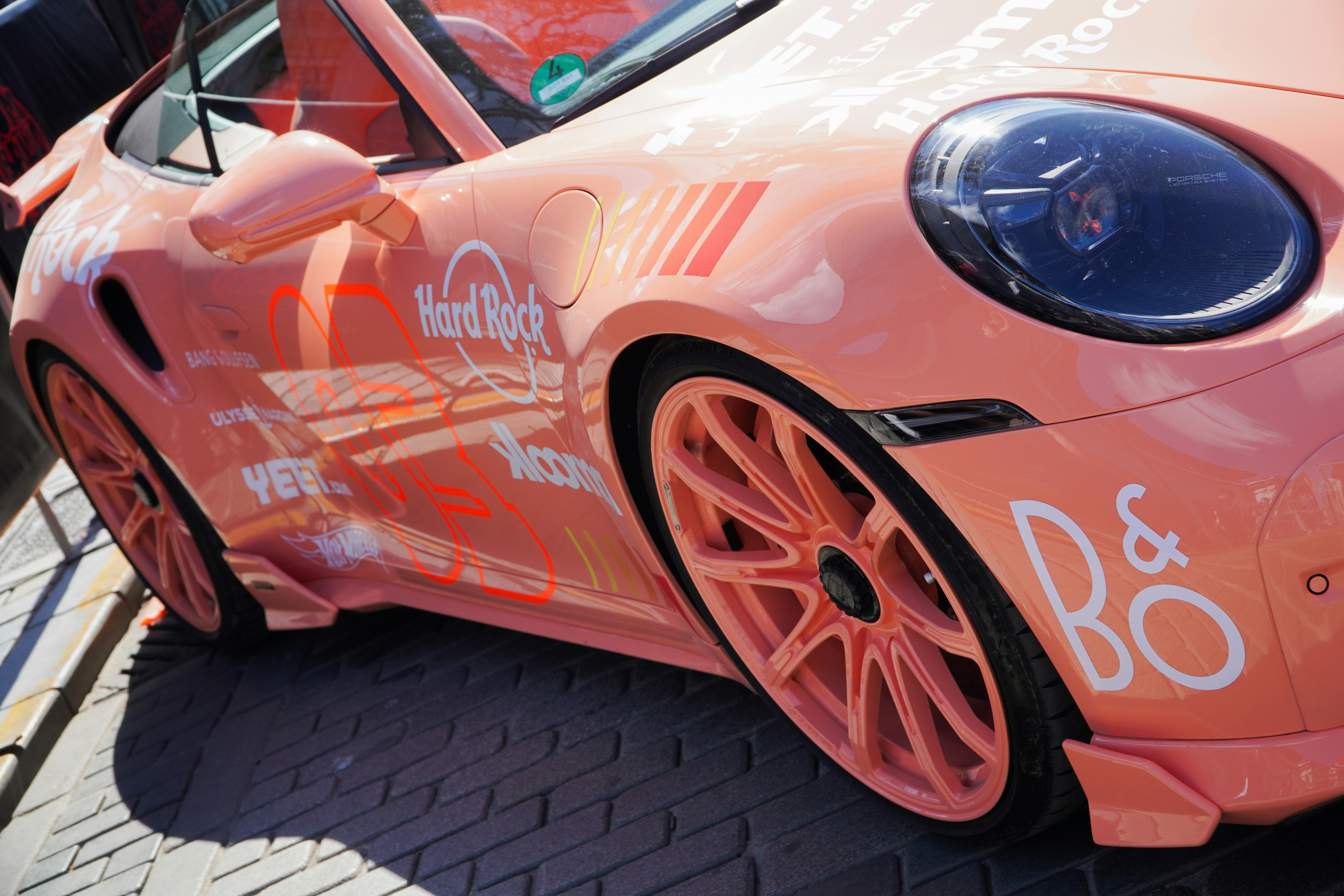 Peach colored porsche with b&o logo.