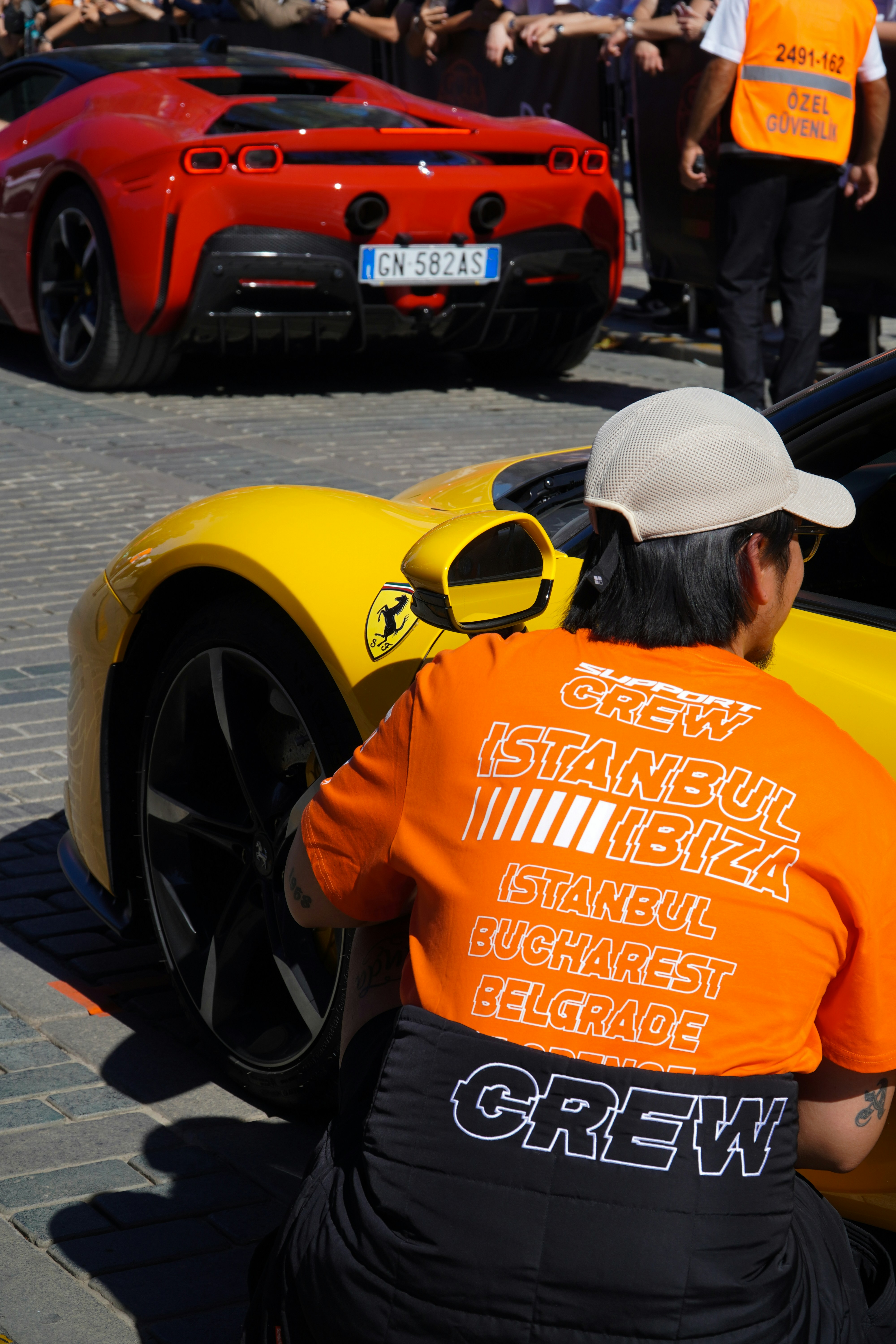 Crew member with orange shirt and yellow ferrari