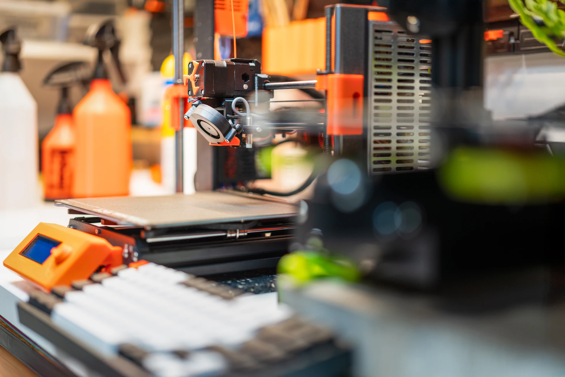 3D printer with orange accents on workbench.