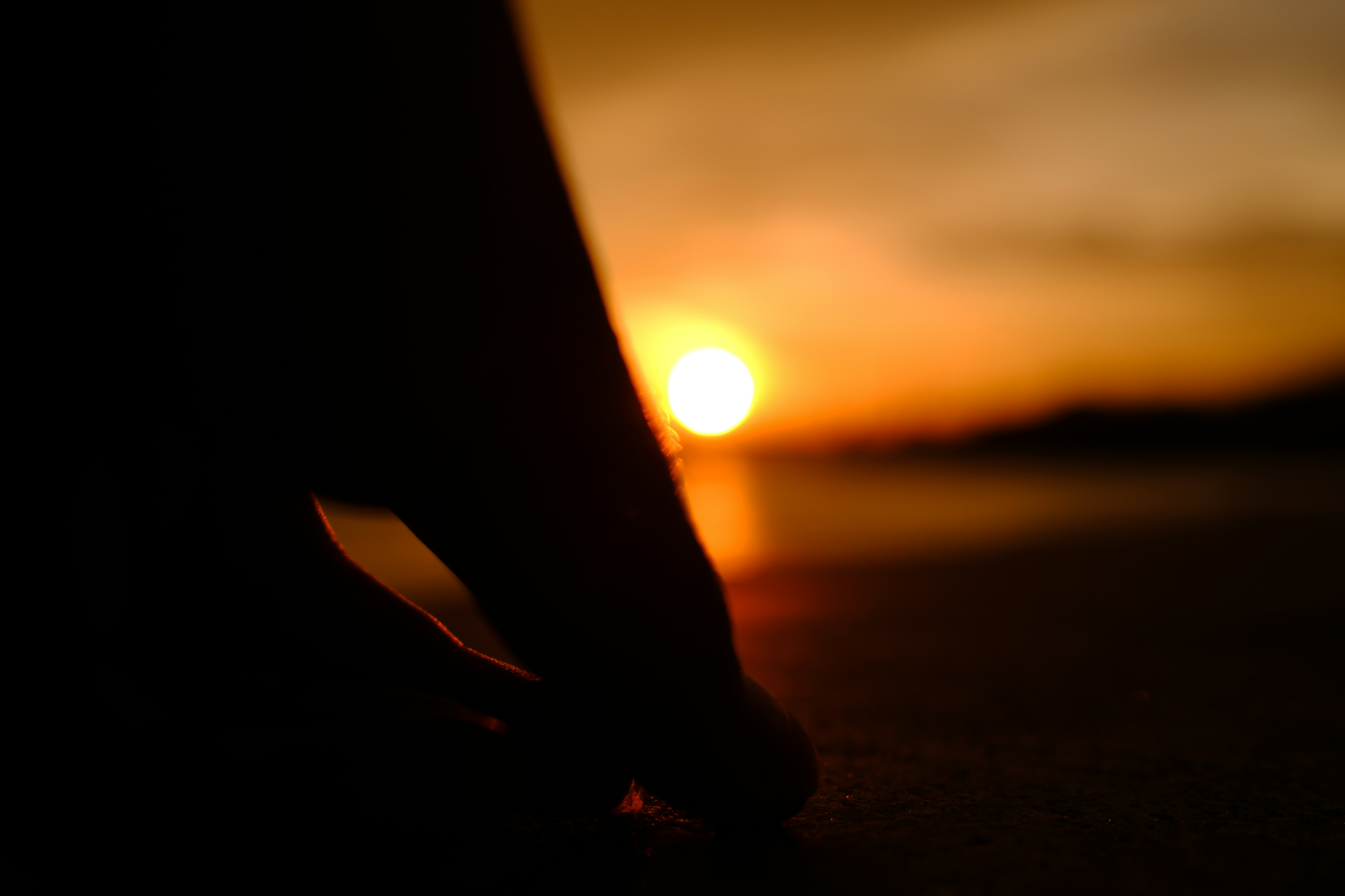 Silhouette reaching toward sunset