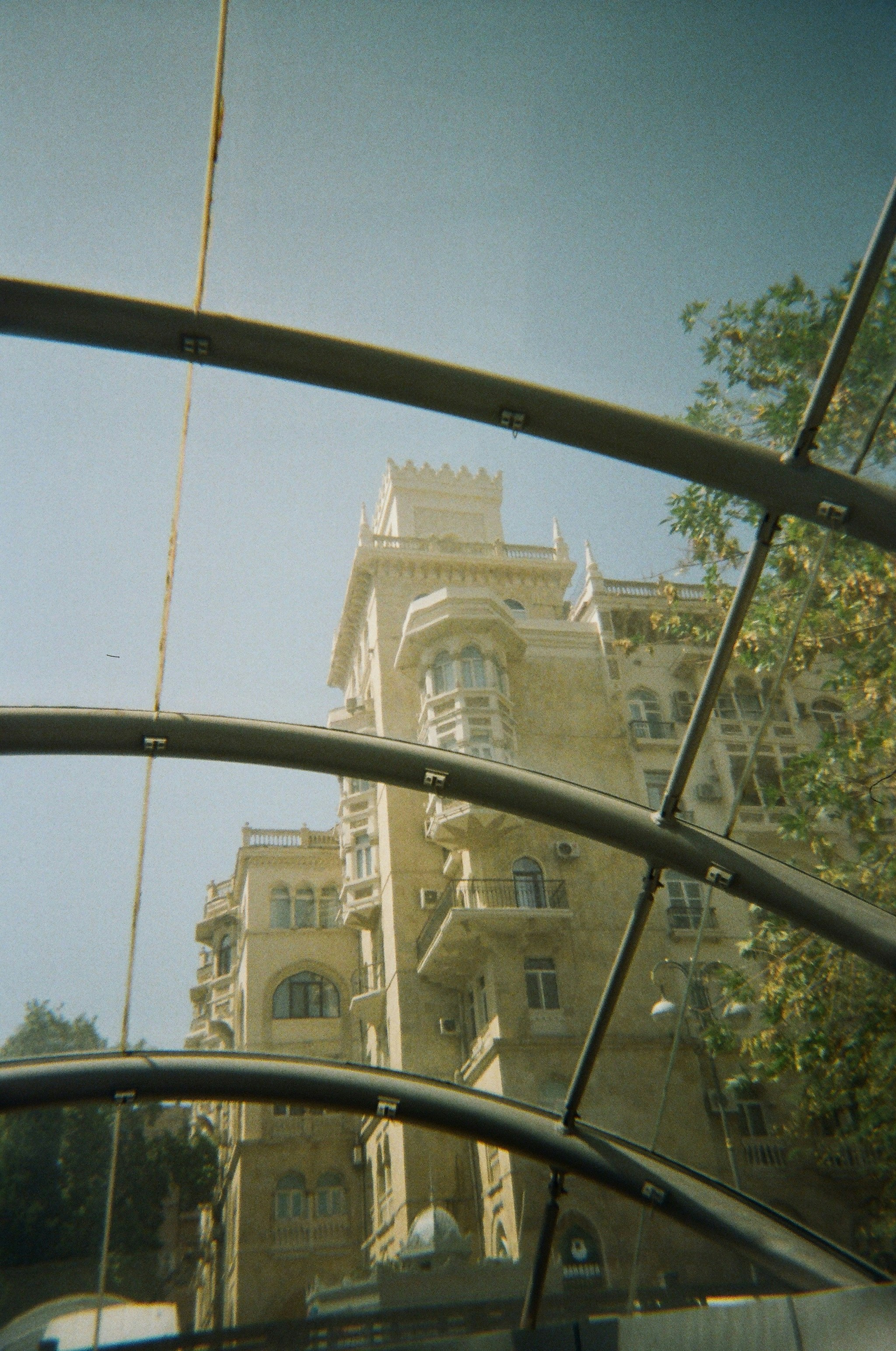 Tall building with ornate balconies seen through glass.