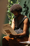 Man with afro reading a newspaper indoors