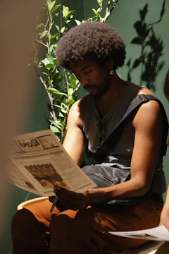 Man with afro reading a newspaper indoors