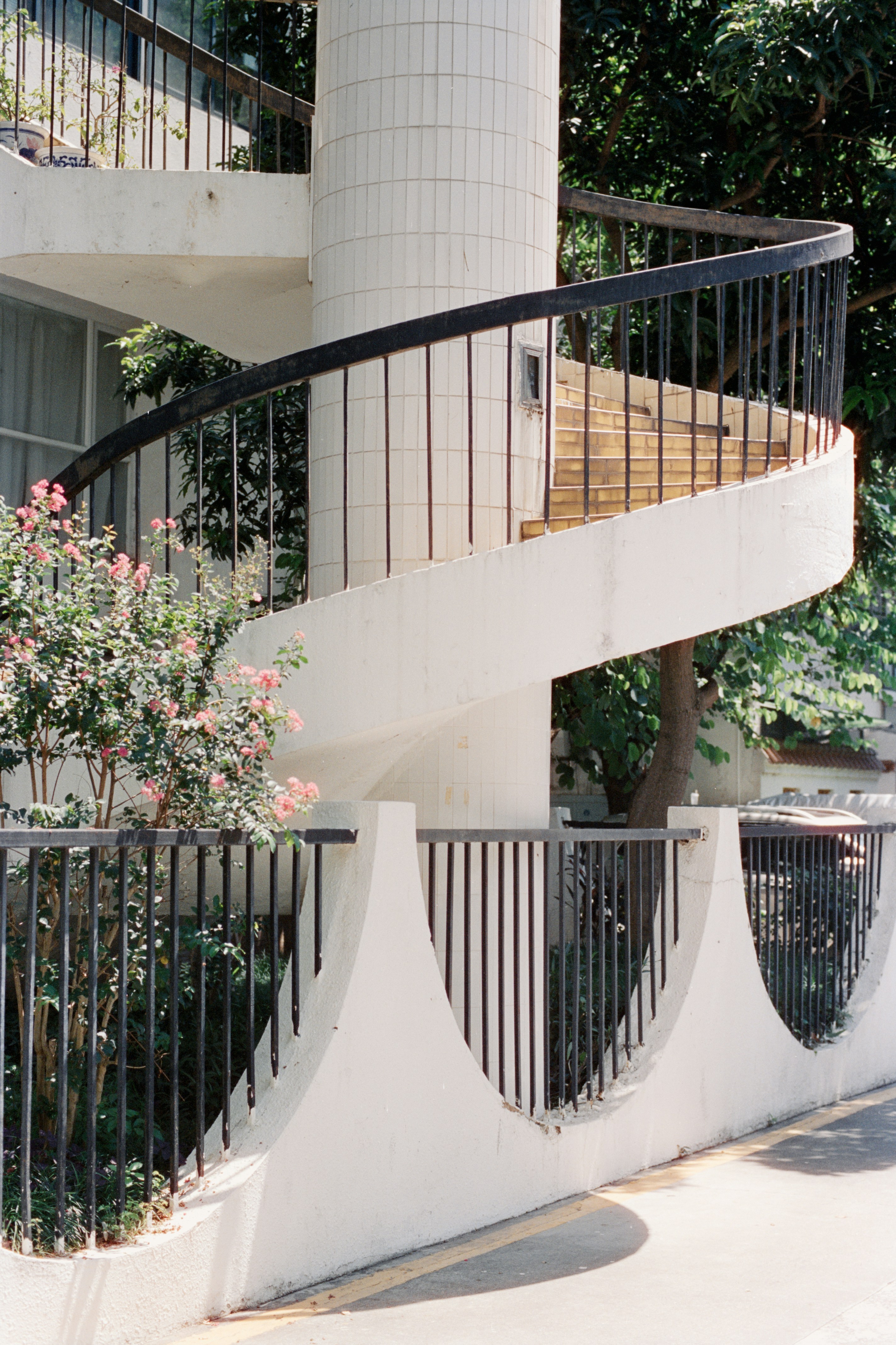White spiral staircase with black railings and plants