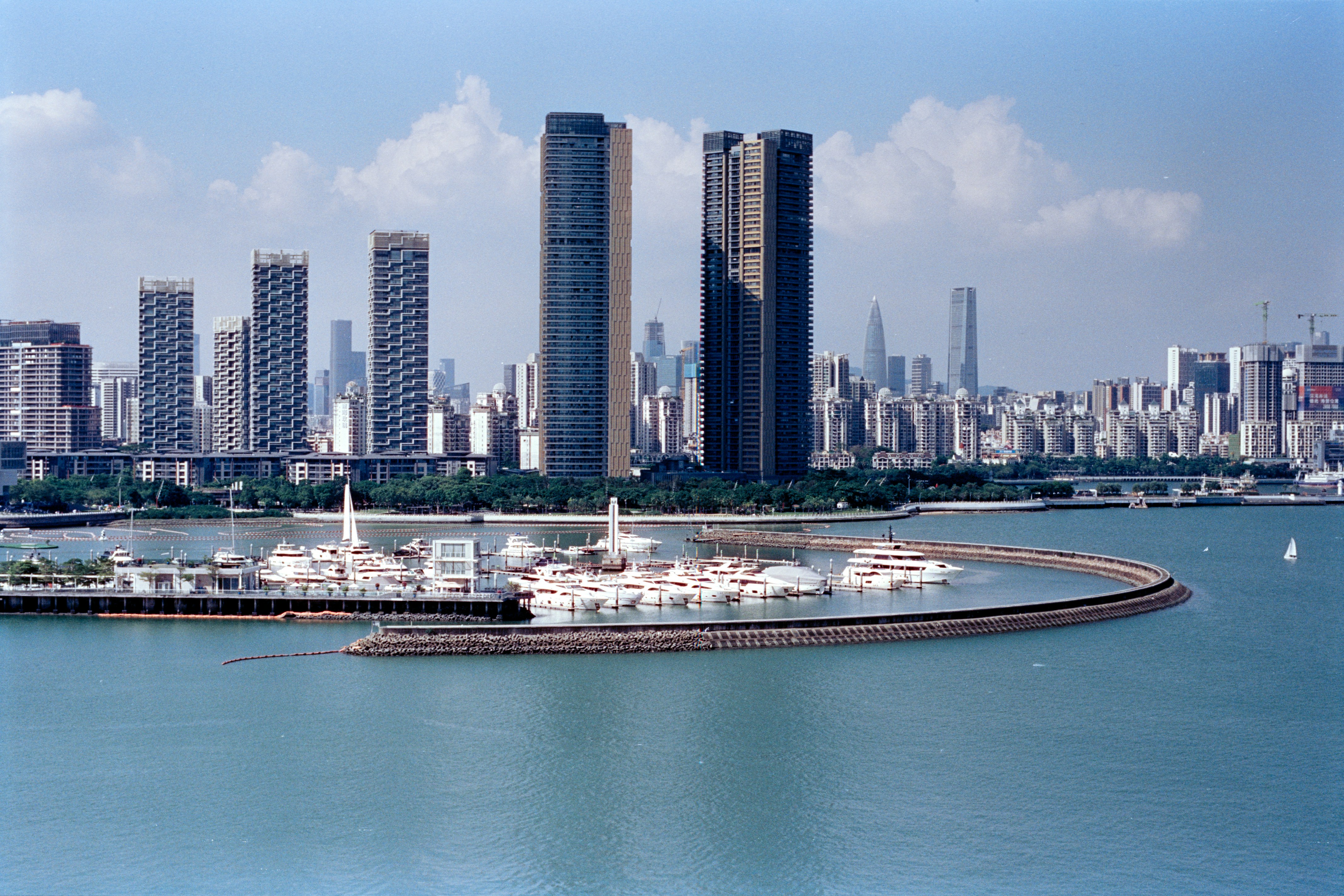 Modern cityscape with yachts docked in a harbor.