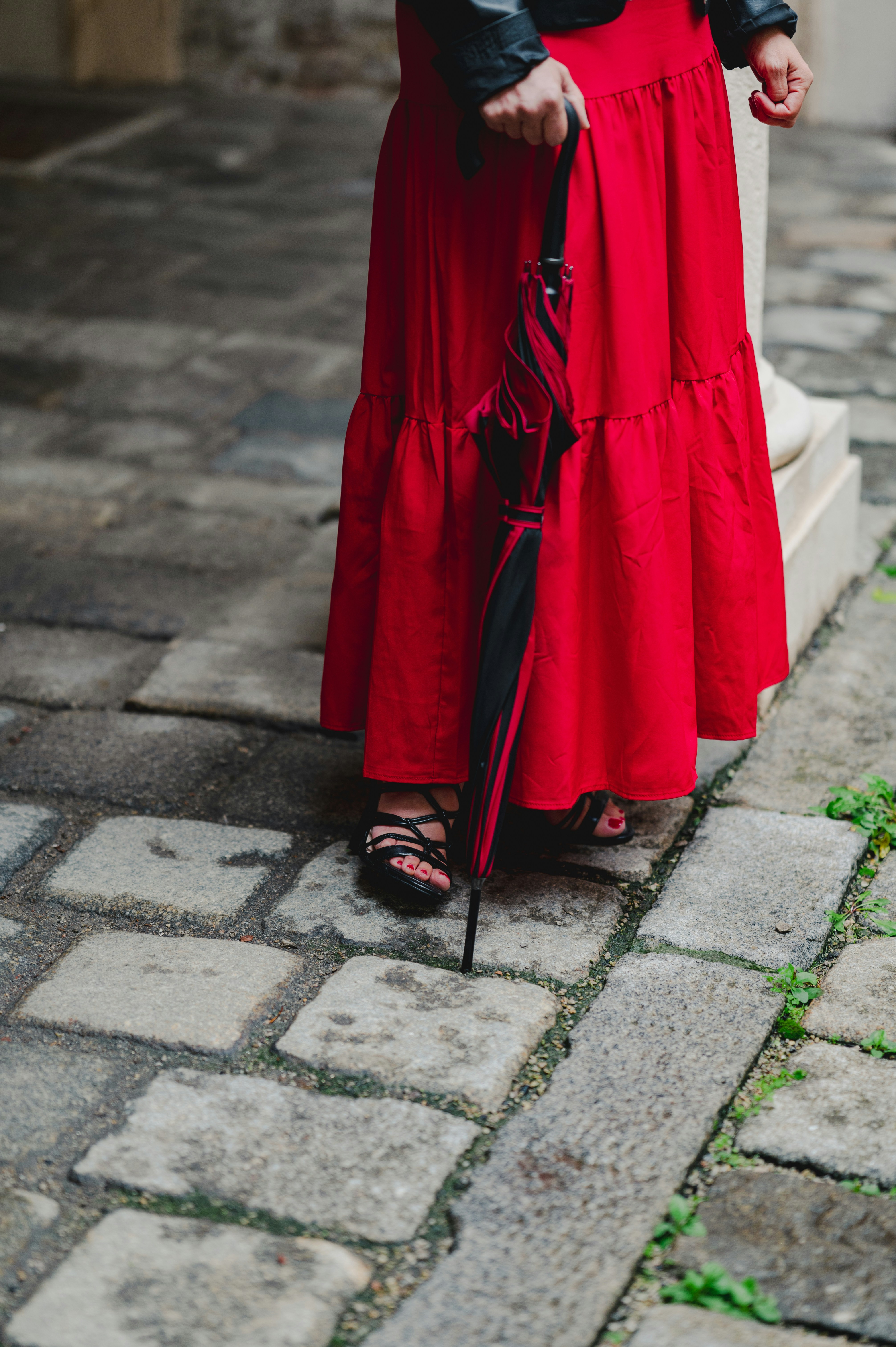 Woman in red dress holding a folded umbrella