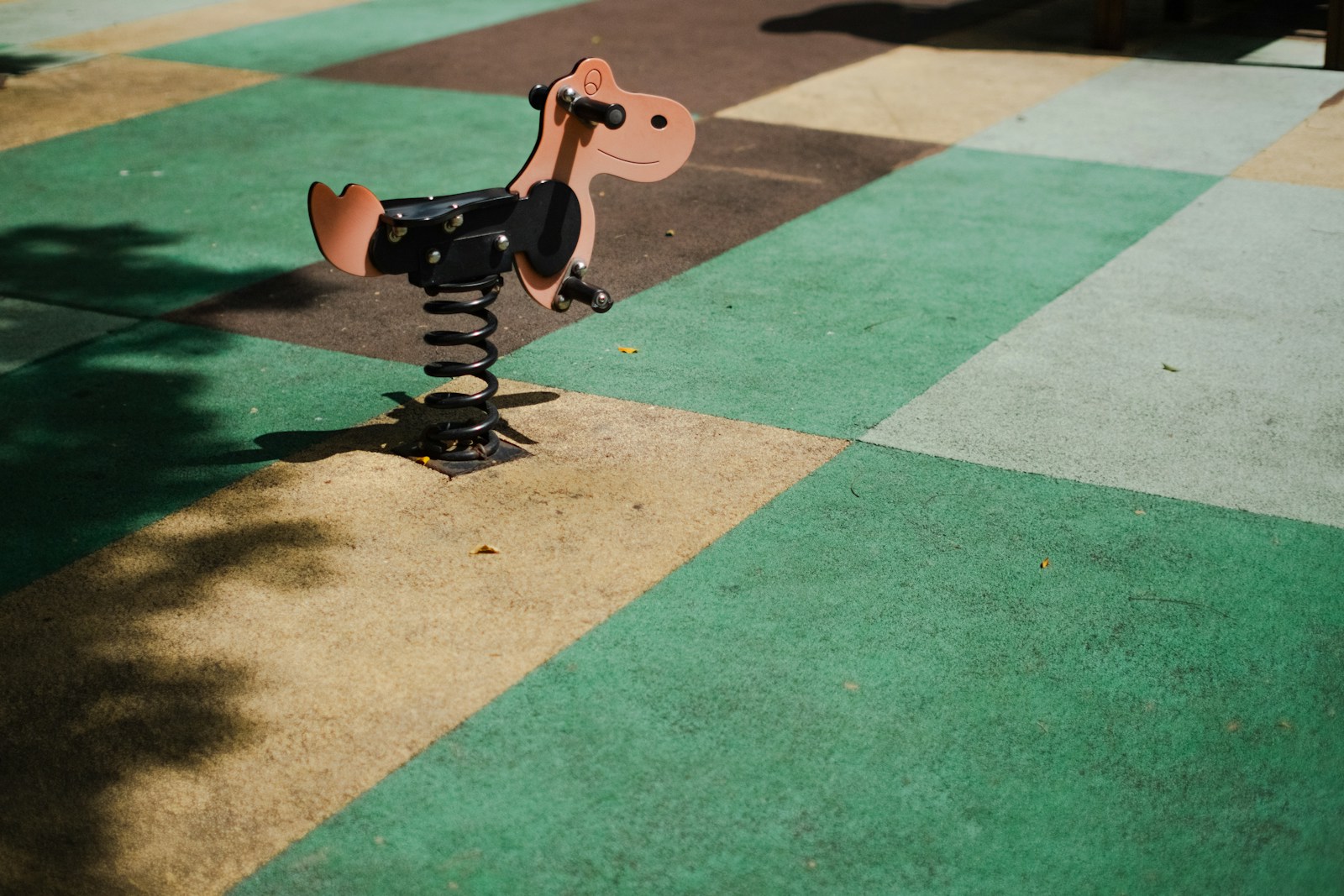 A spring rider on a checkered rubber play surface