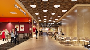 People walking through a modern shopping mall interior.