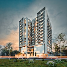 Modern apartment building at dusk with cars passing.