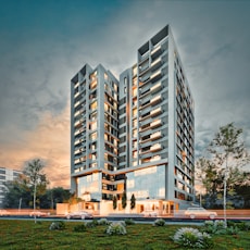 Modern apartment building at dusk with cars passing.