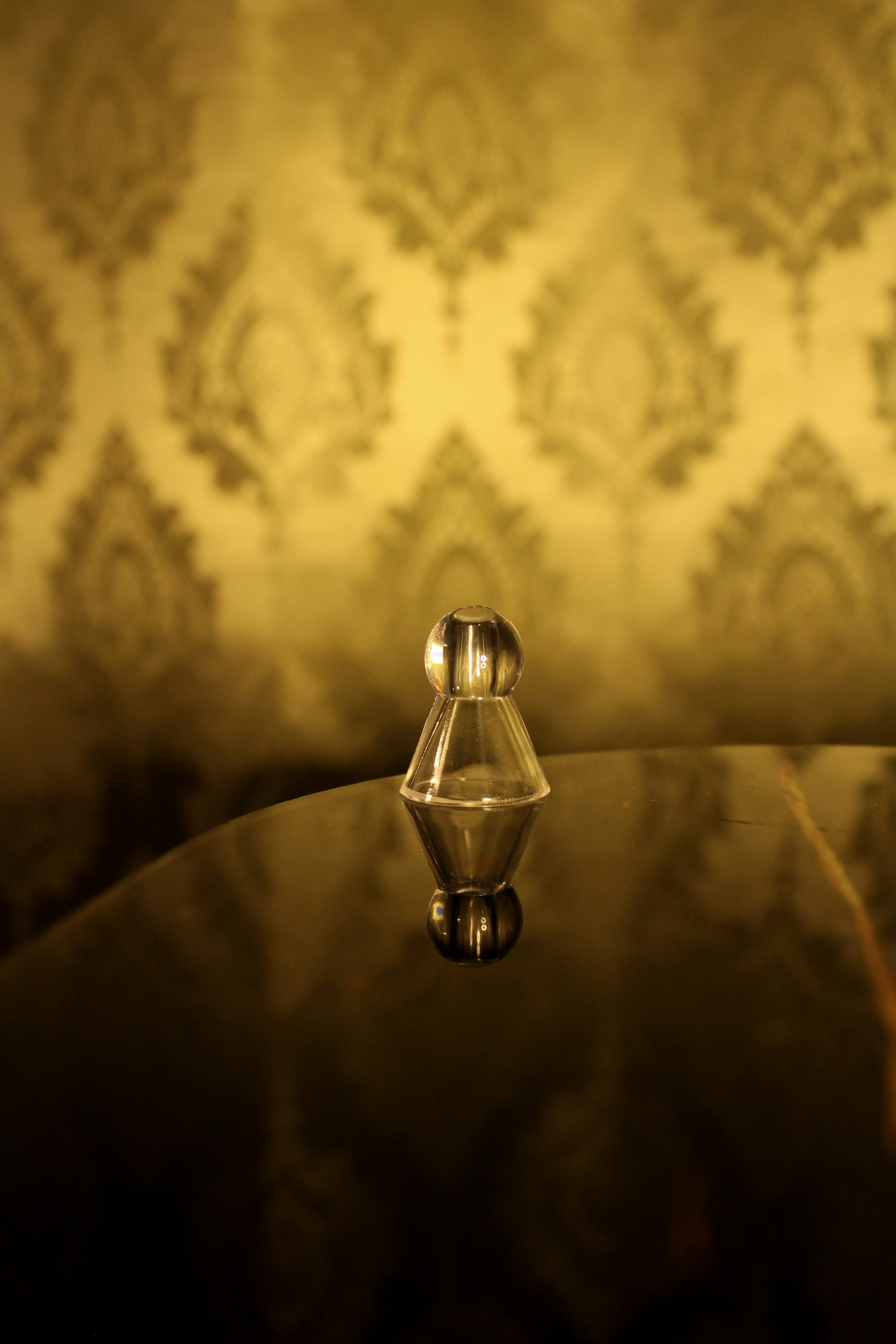 Small glass object on a reflective surface.