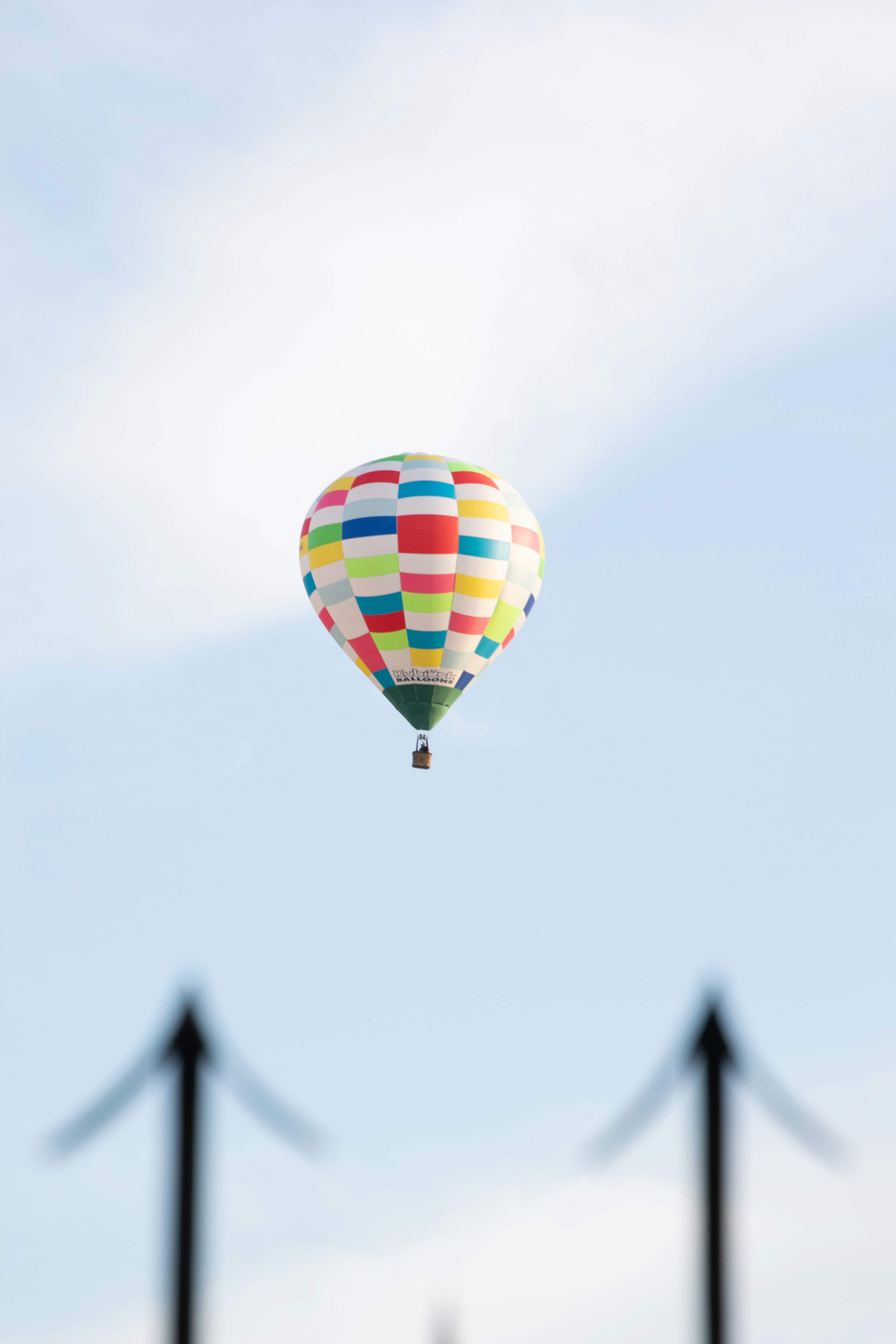Colorful hot air balloon floats in a pale blue sky.
