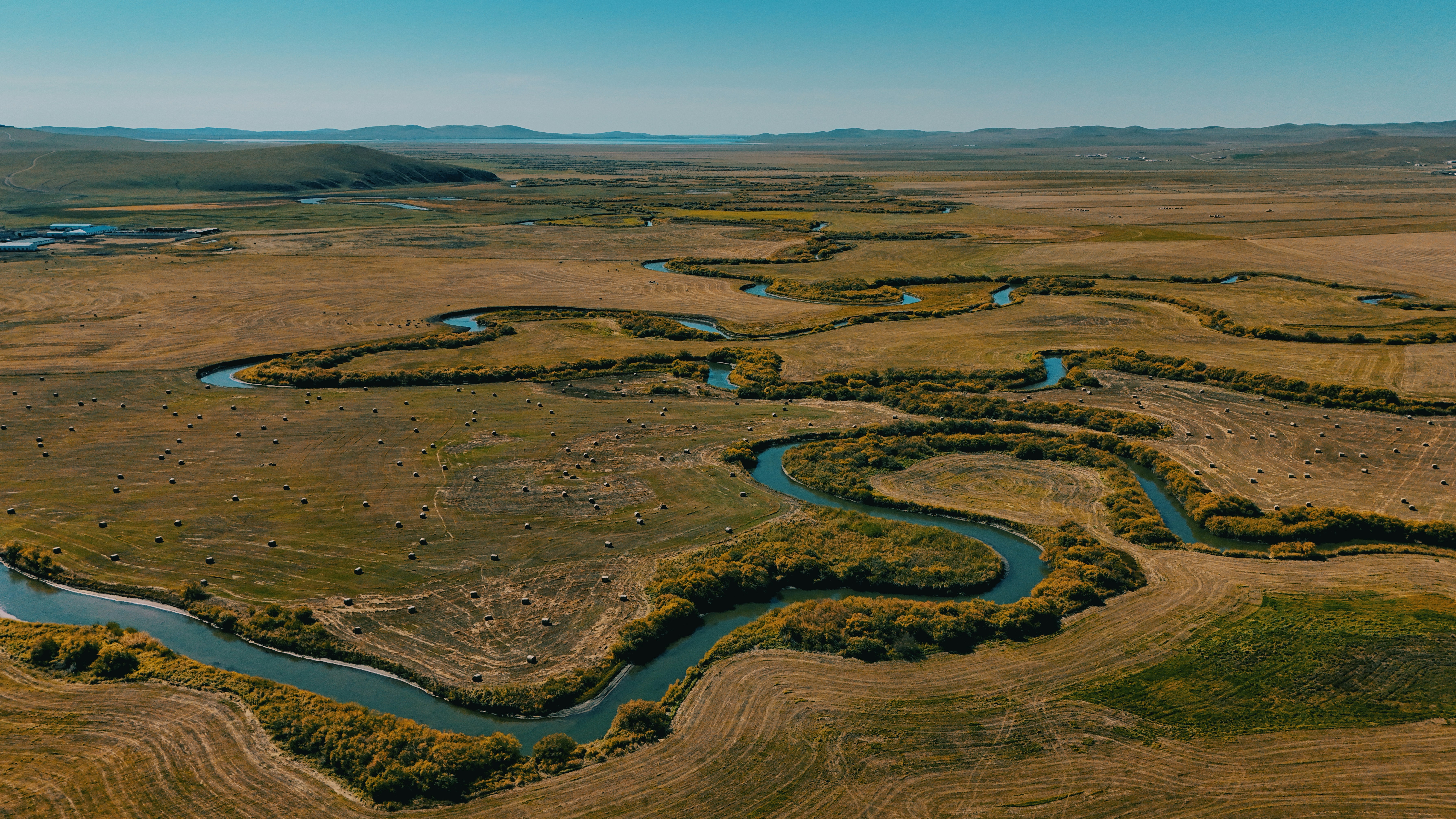 Meandering river through a vast, dry grassland landscape.