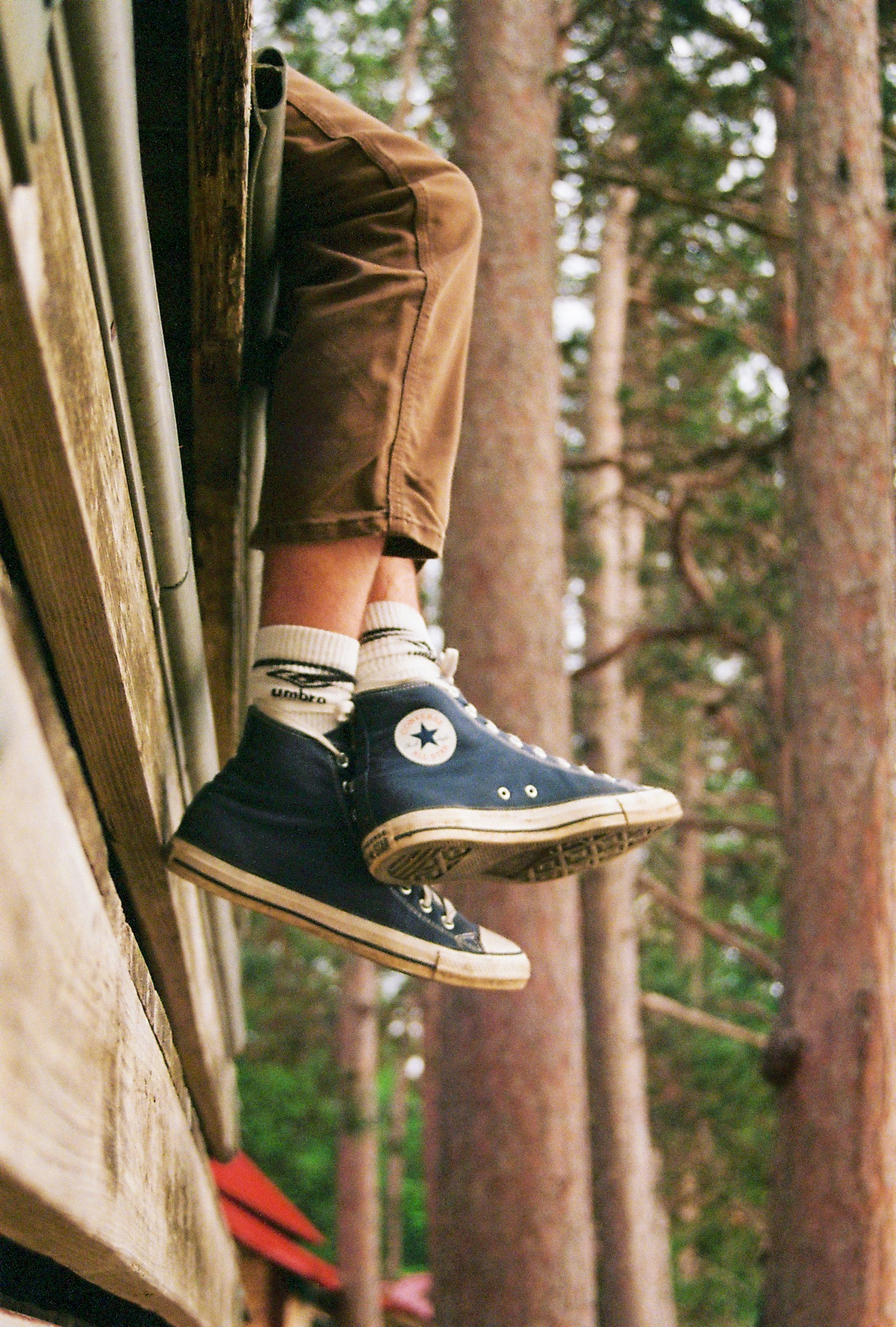 Person wearing blue high-top sneakers and brown pants outdoors.