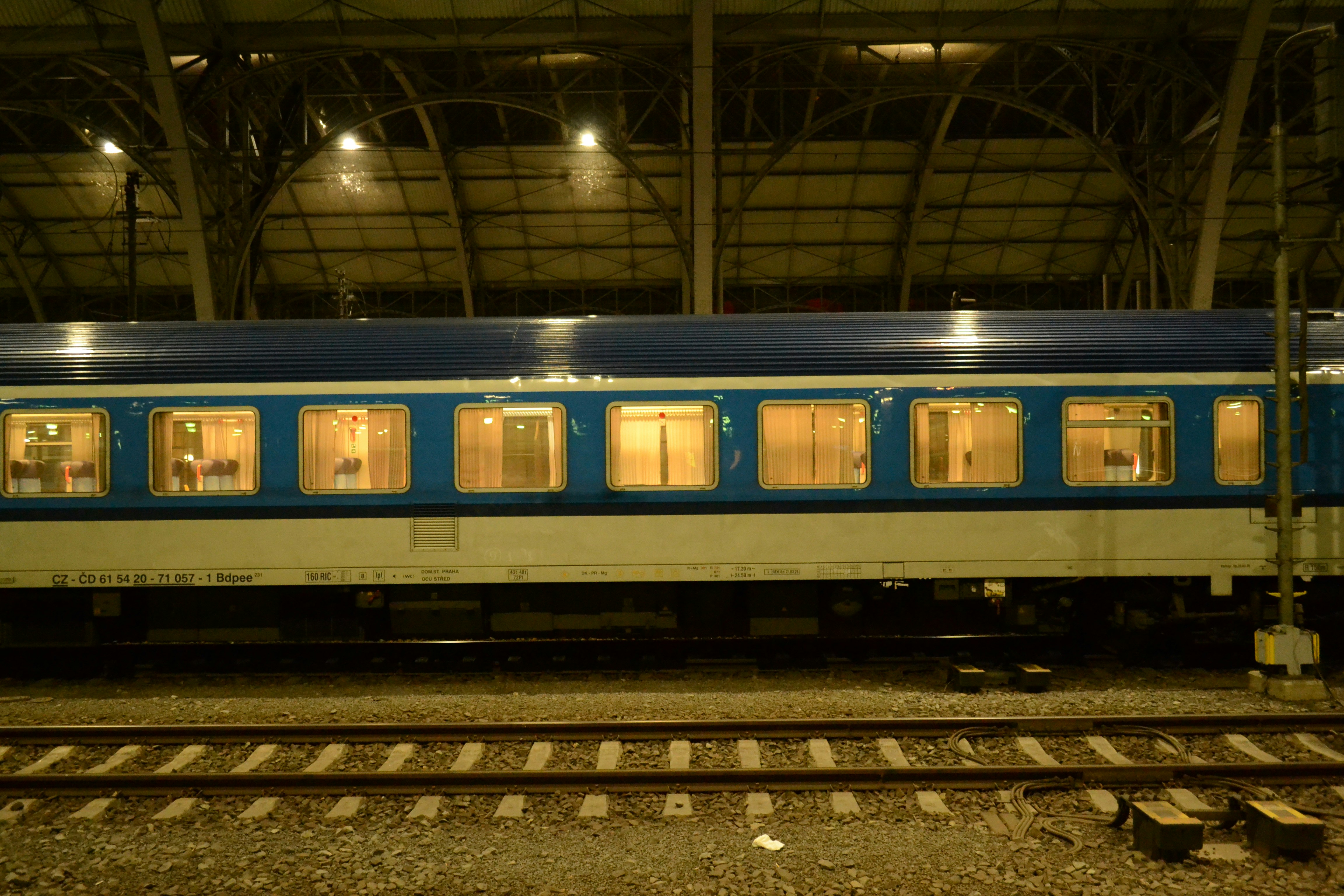 Blue train car with illuminated windows at station