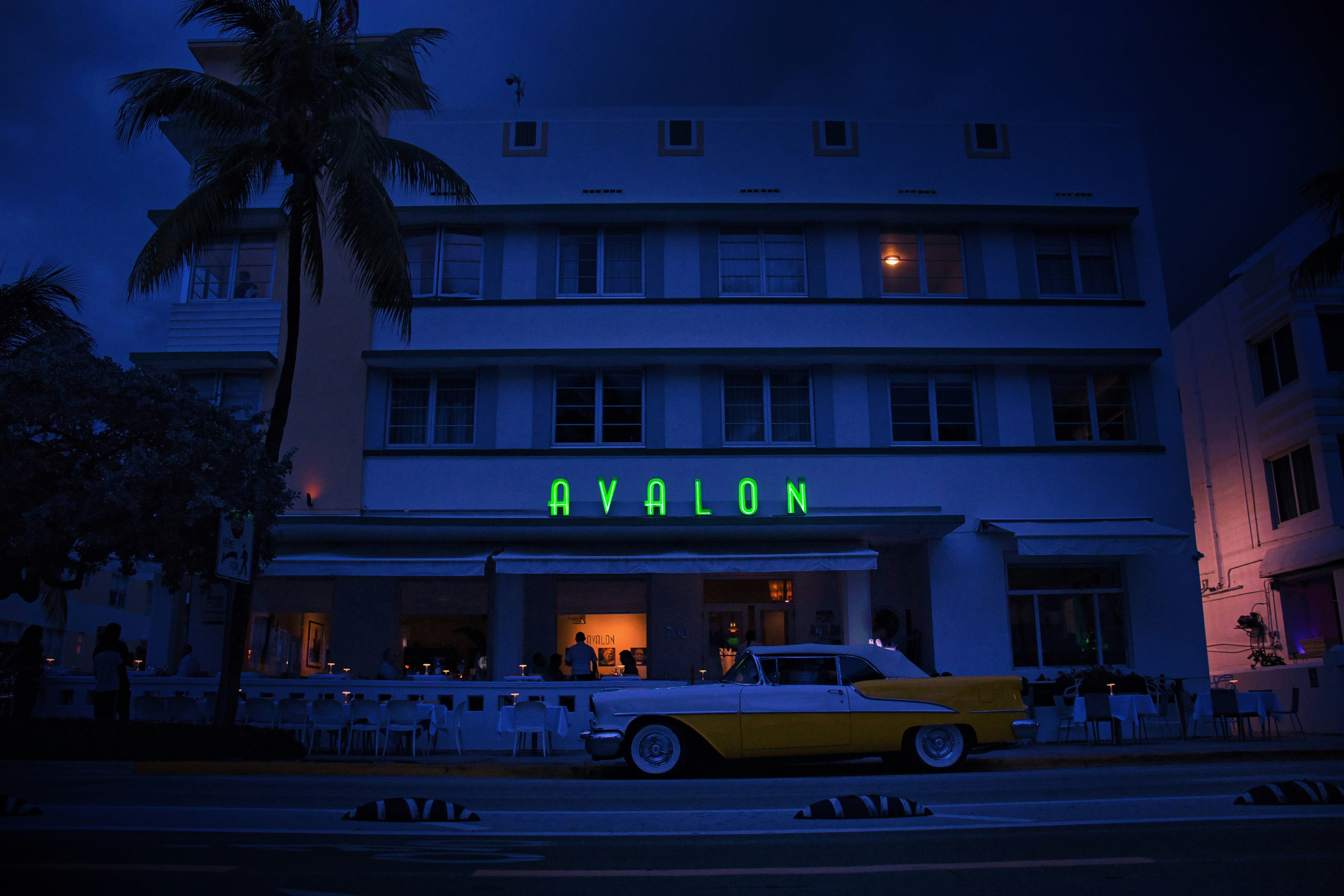 Retro hotel with neon sign and vintage car at night