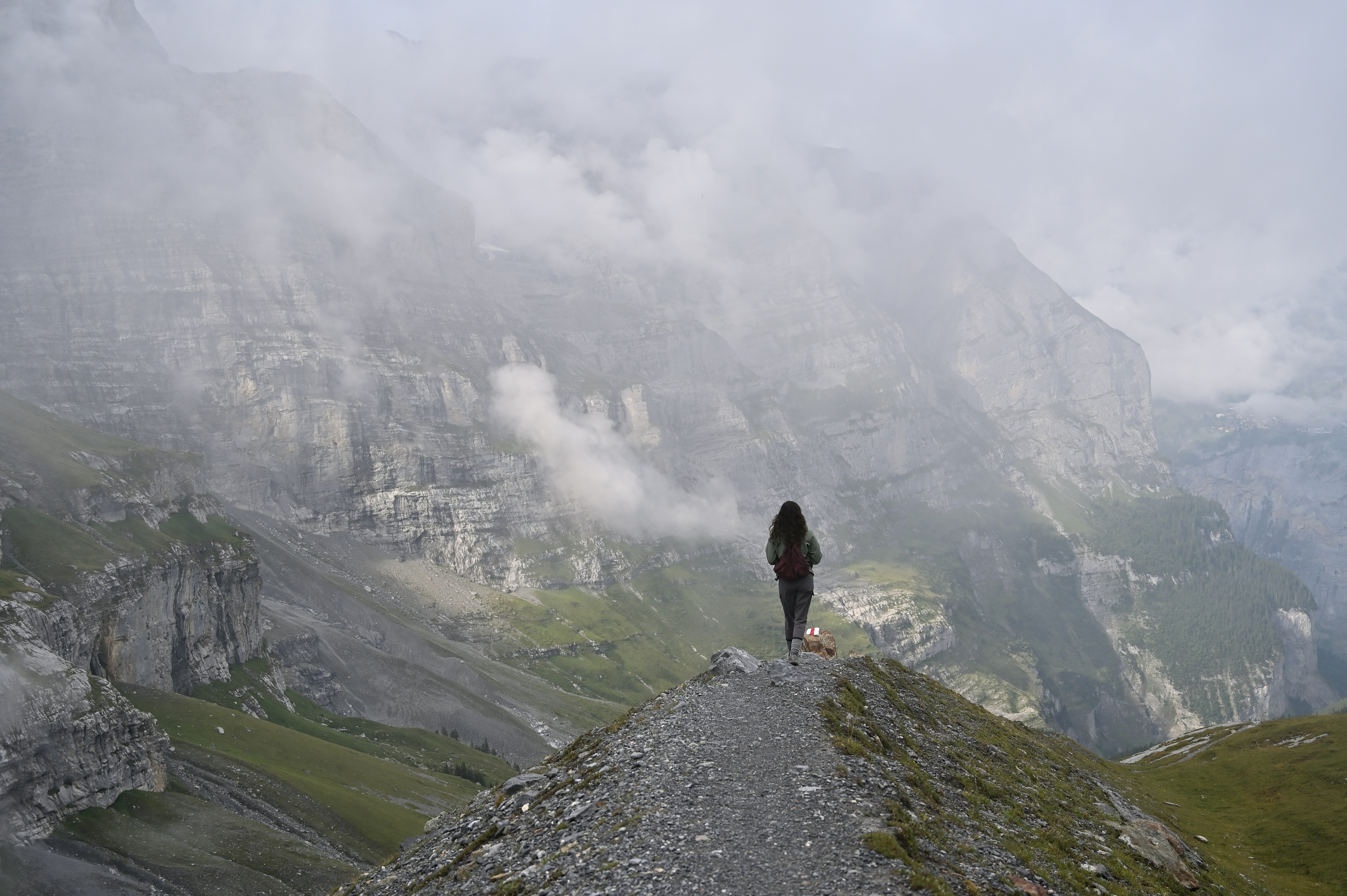 Una figura solitaria si trova su un crinale montuoso nella nebbia.