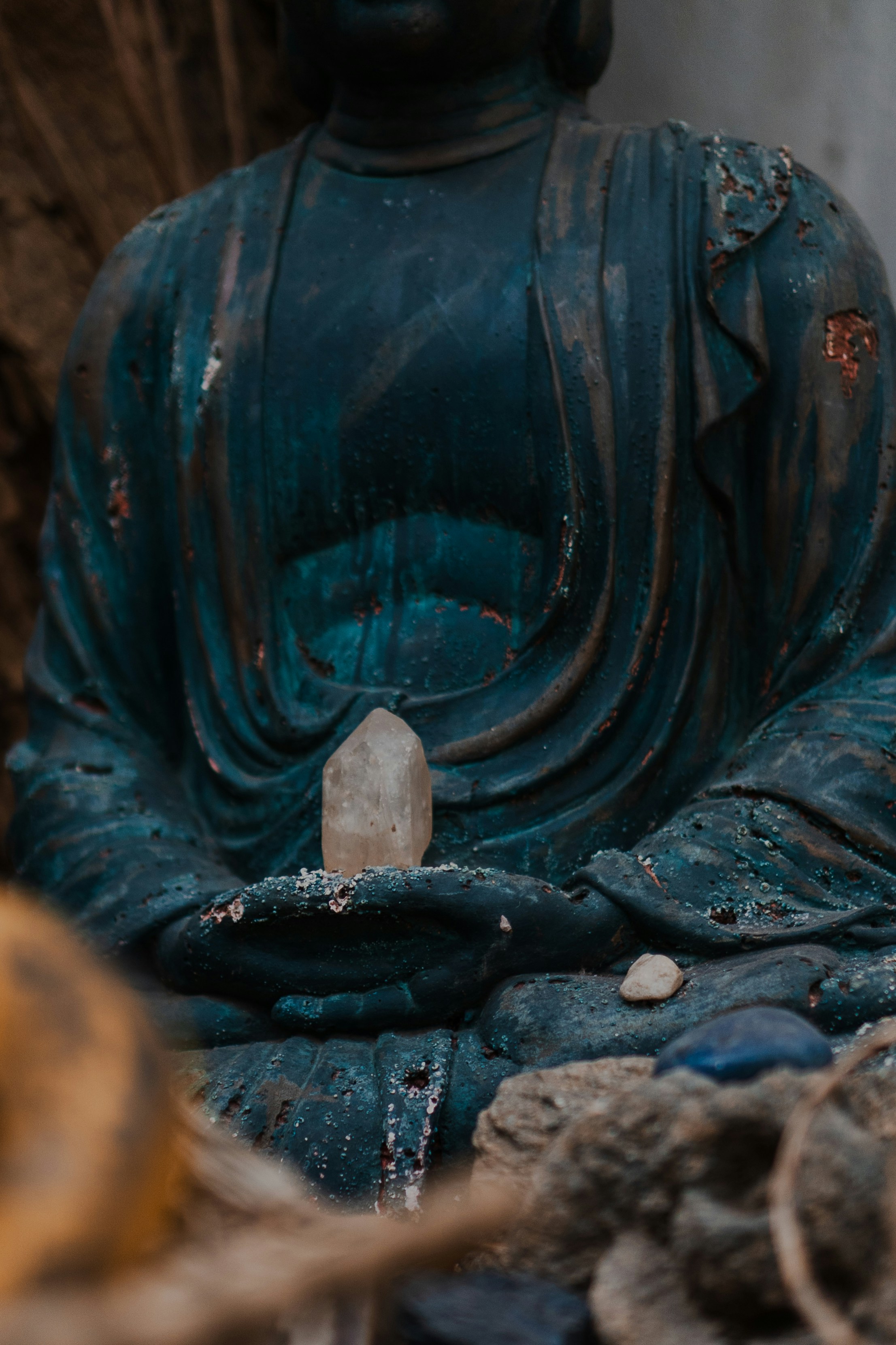 A weathered statue of buddha holding a crystal.