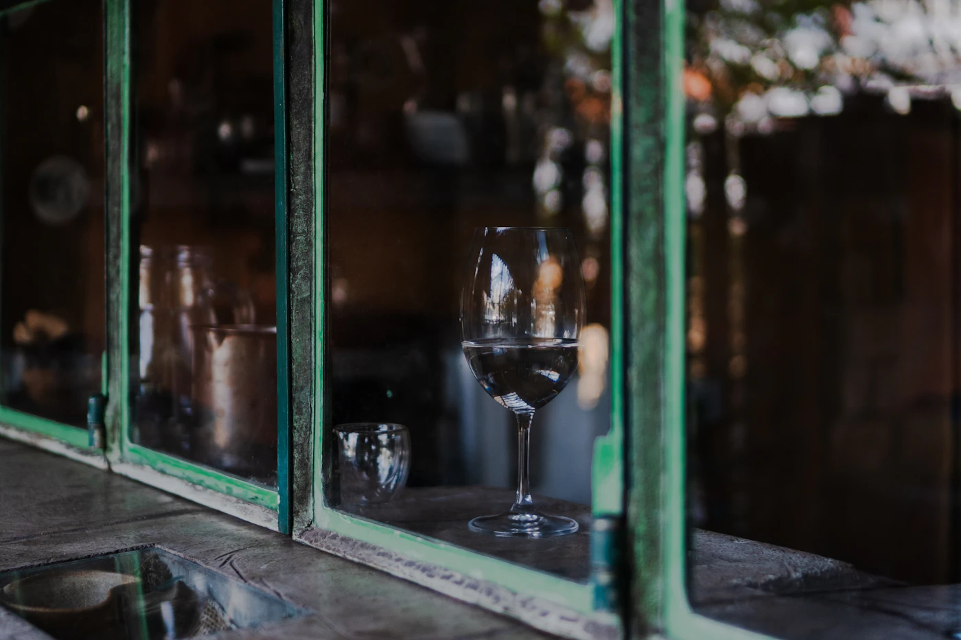 Glas Wasser am Fenster als Symbol für Flüssigkeit und eine ruhige Pause bei Kopfschmerzen