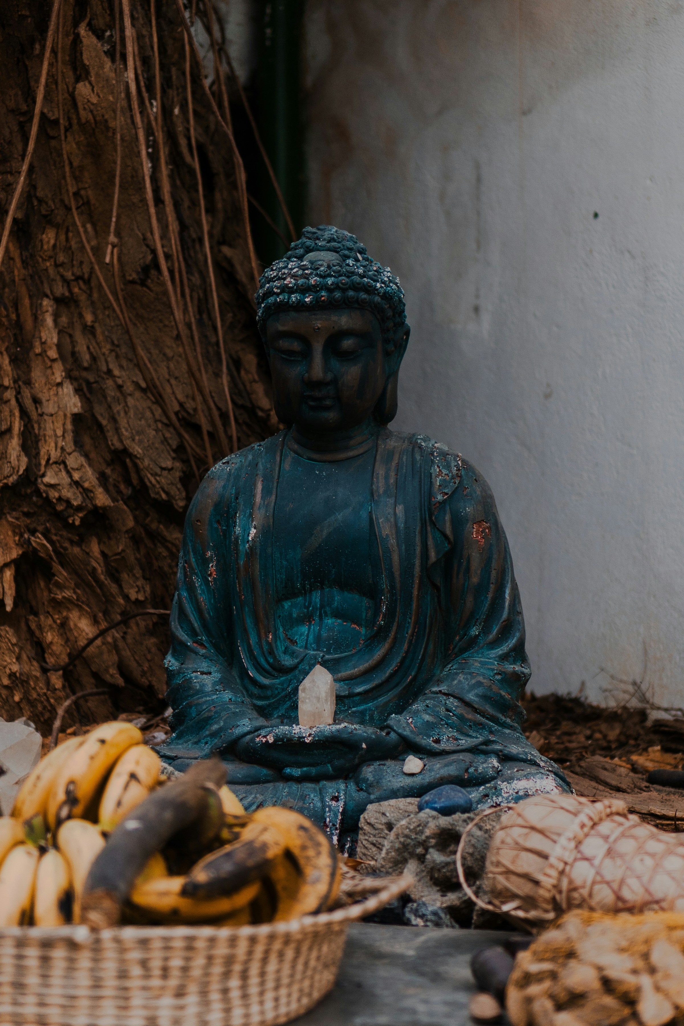 Buddha statue sits with bananas in a basket.