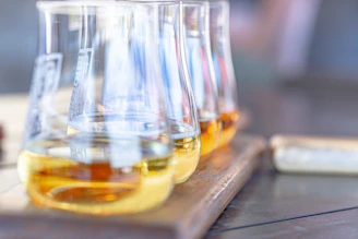 Three beakers with yellow liquid on wooden board