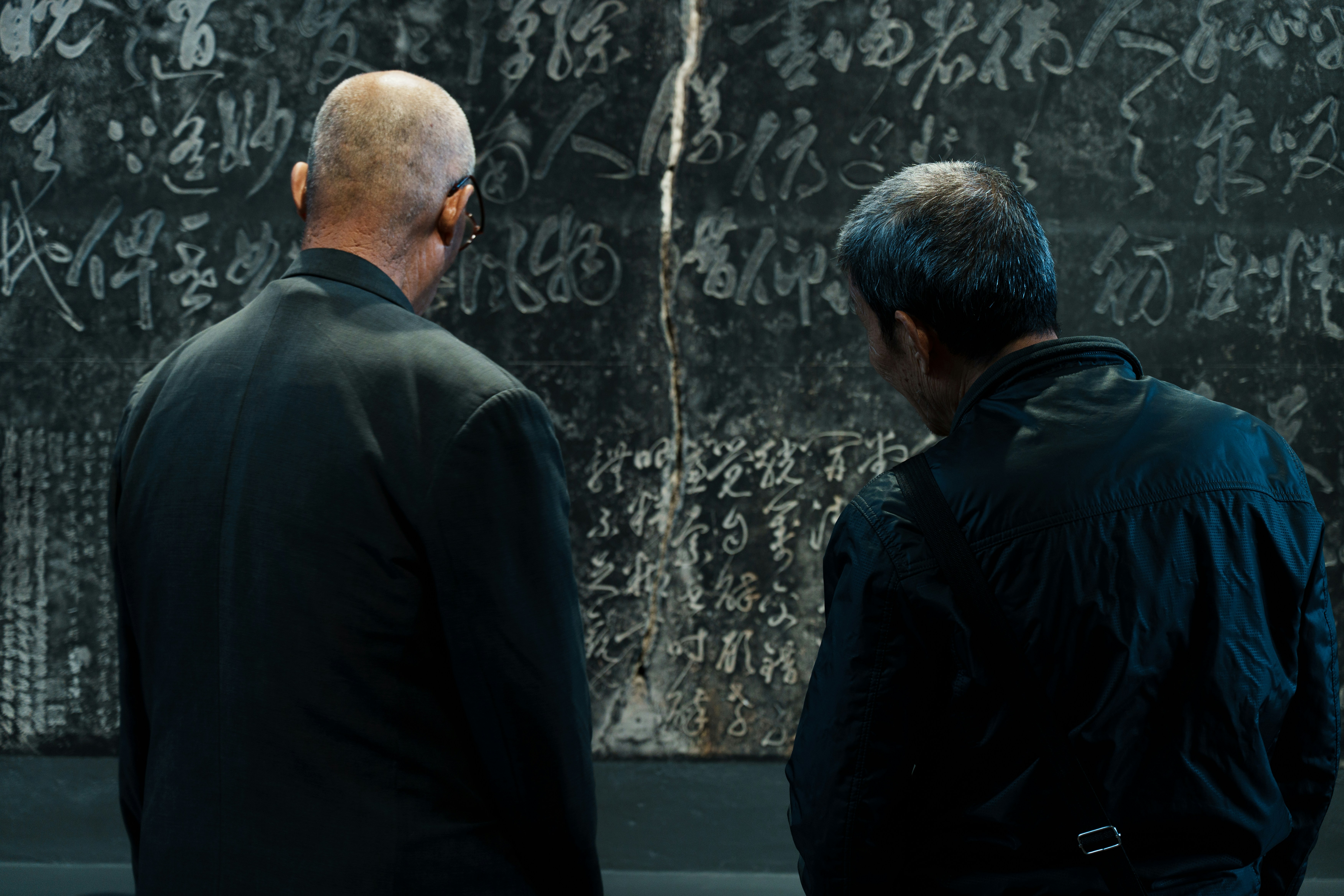 Two men examine ancient inscriptions on a stone tablet