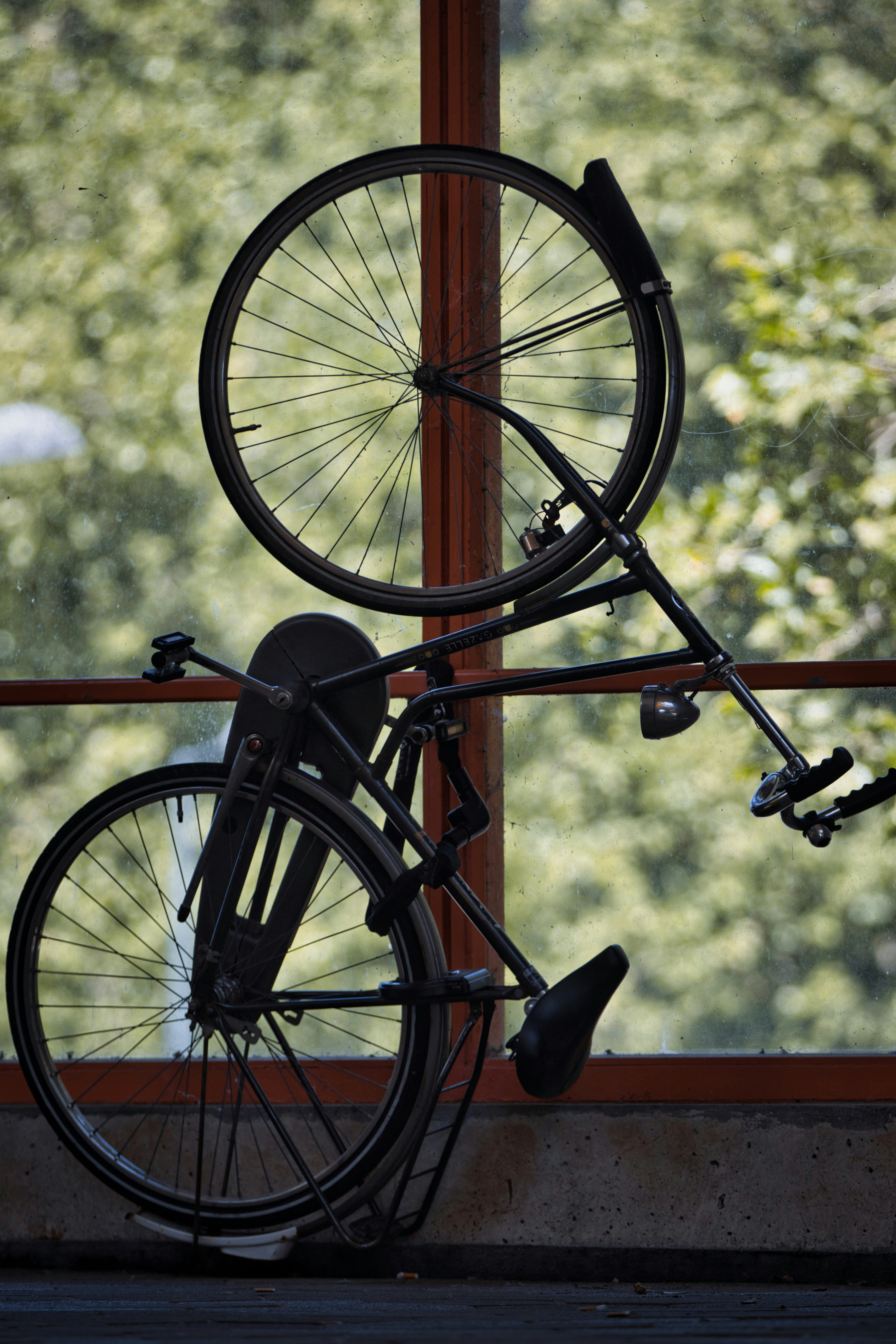 A black bicycle is mounted vertically indoors.