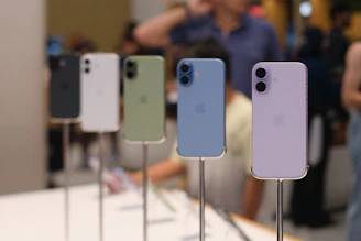 Five iphones displayed in various colors on stands.