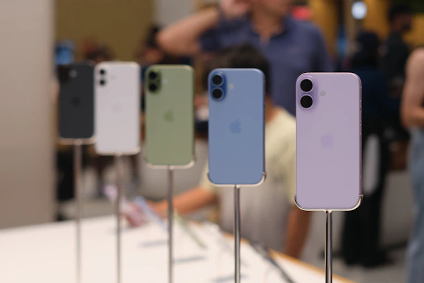 Five iphones displayed in various colors on stands.