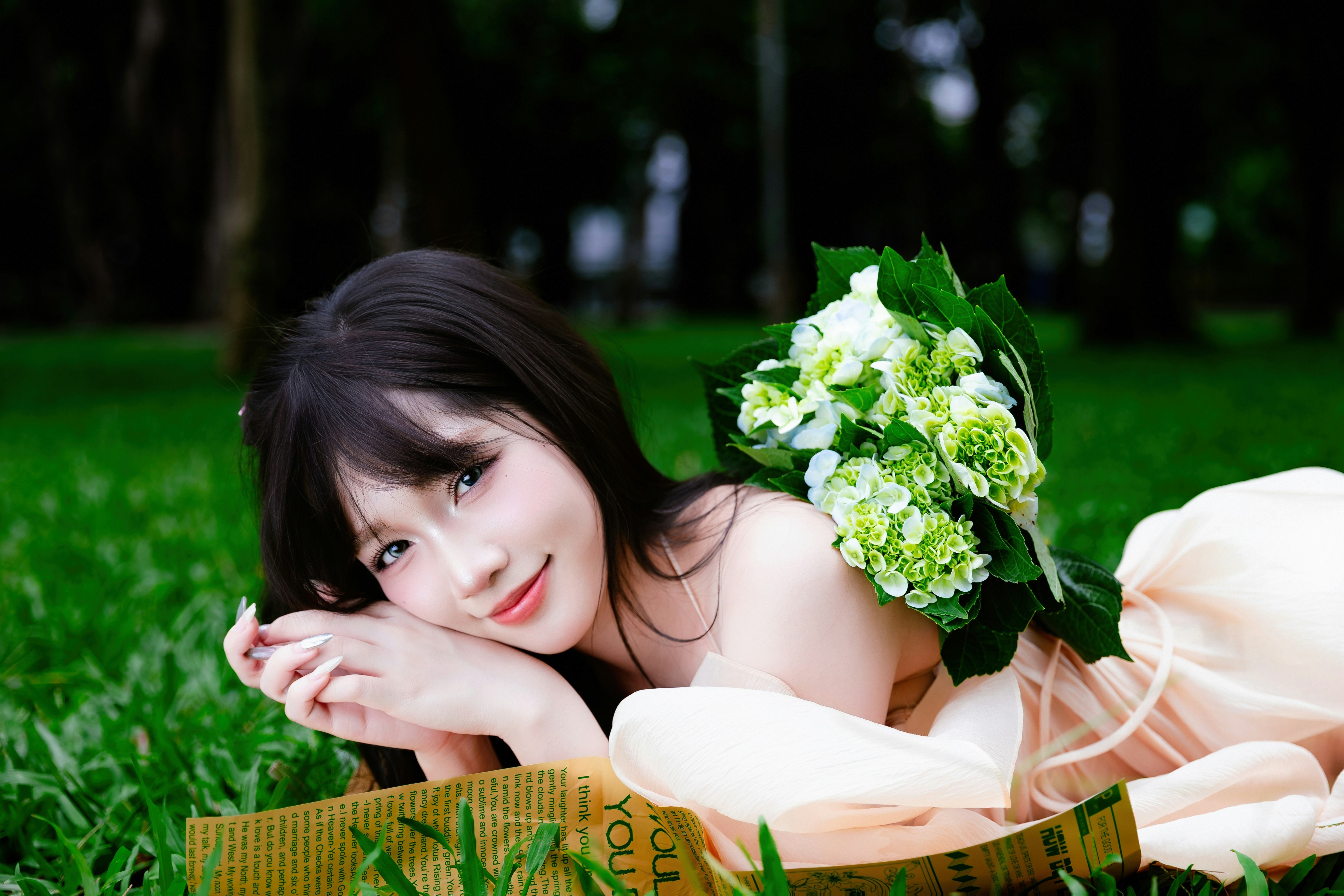 Young woman with flowers lying on grass