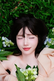 Young woman with eyes closed lying on grass with flowers