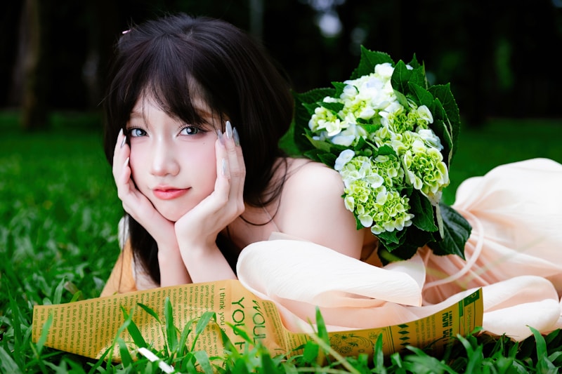 Young woman with flowers lying on grass