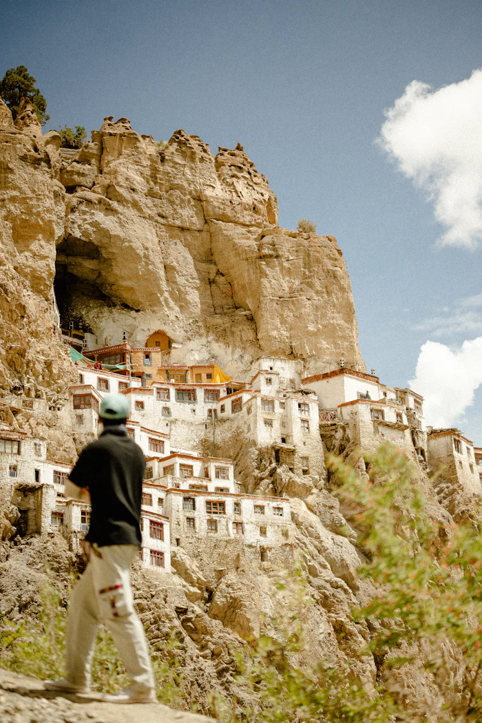 Homme observant un village construit dans la falaise au Ladakh