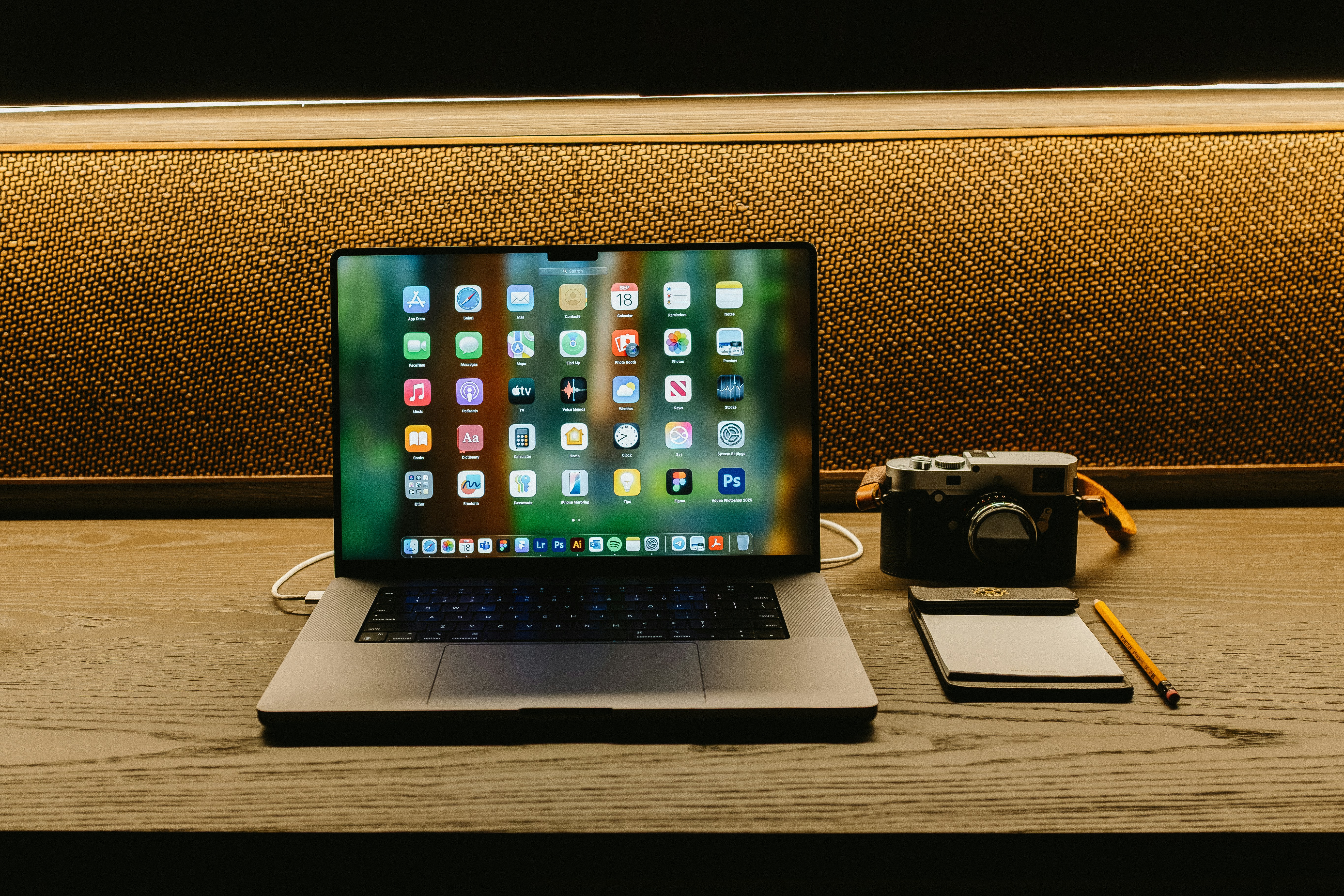 Laptop, camera, and notepad on a wooden desk