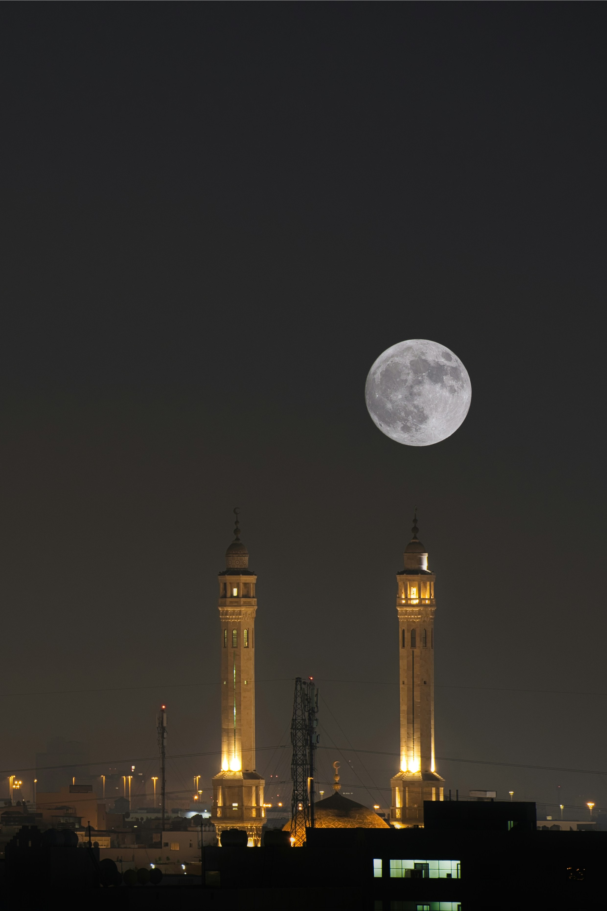 La luna llena se eleva sobre las torres iluminadas de las mezquitas por la noche