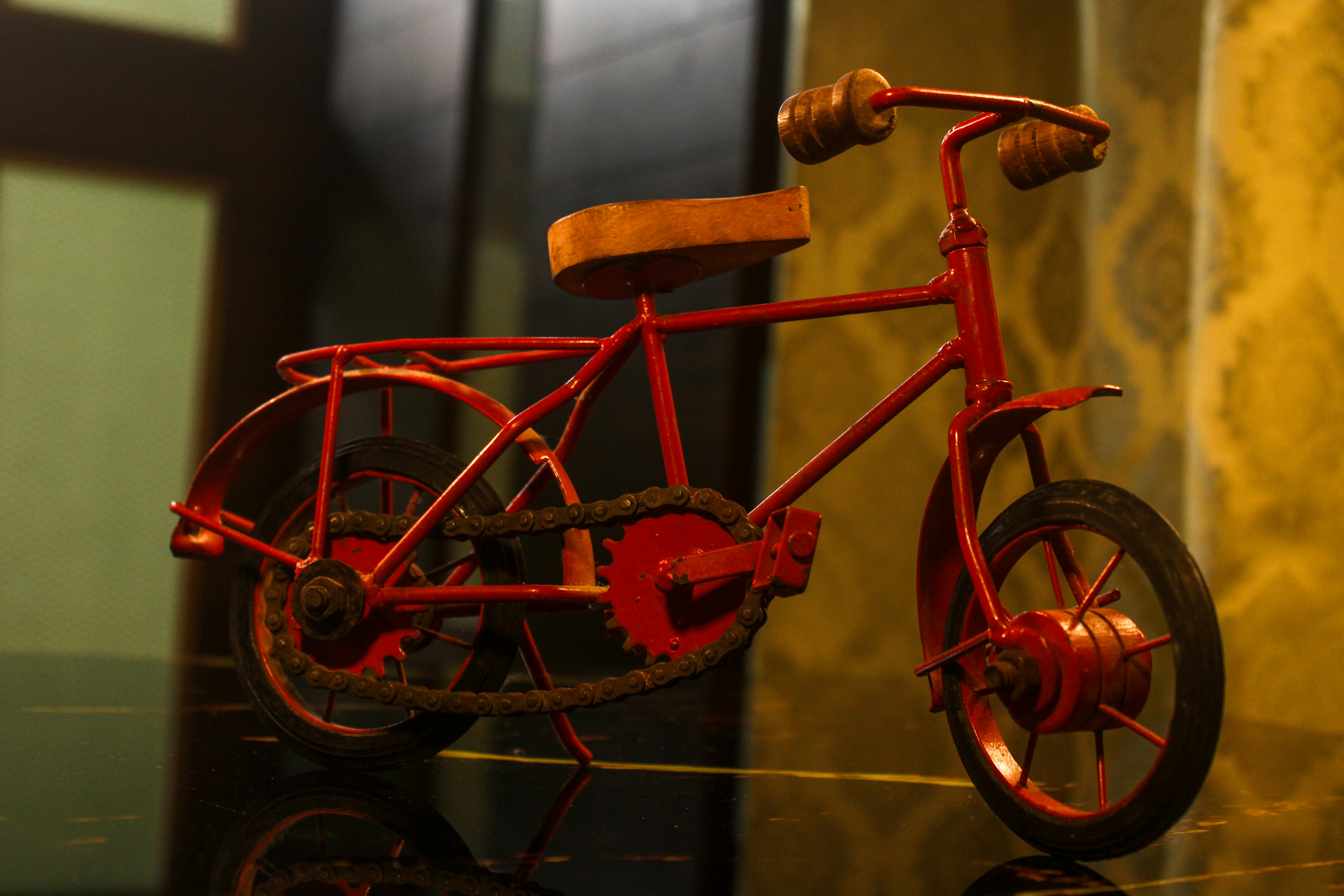 A small, red vintage bicycle with a brown seat.
