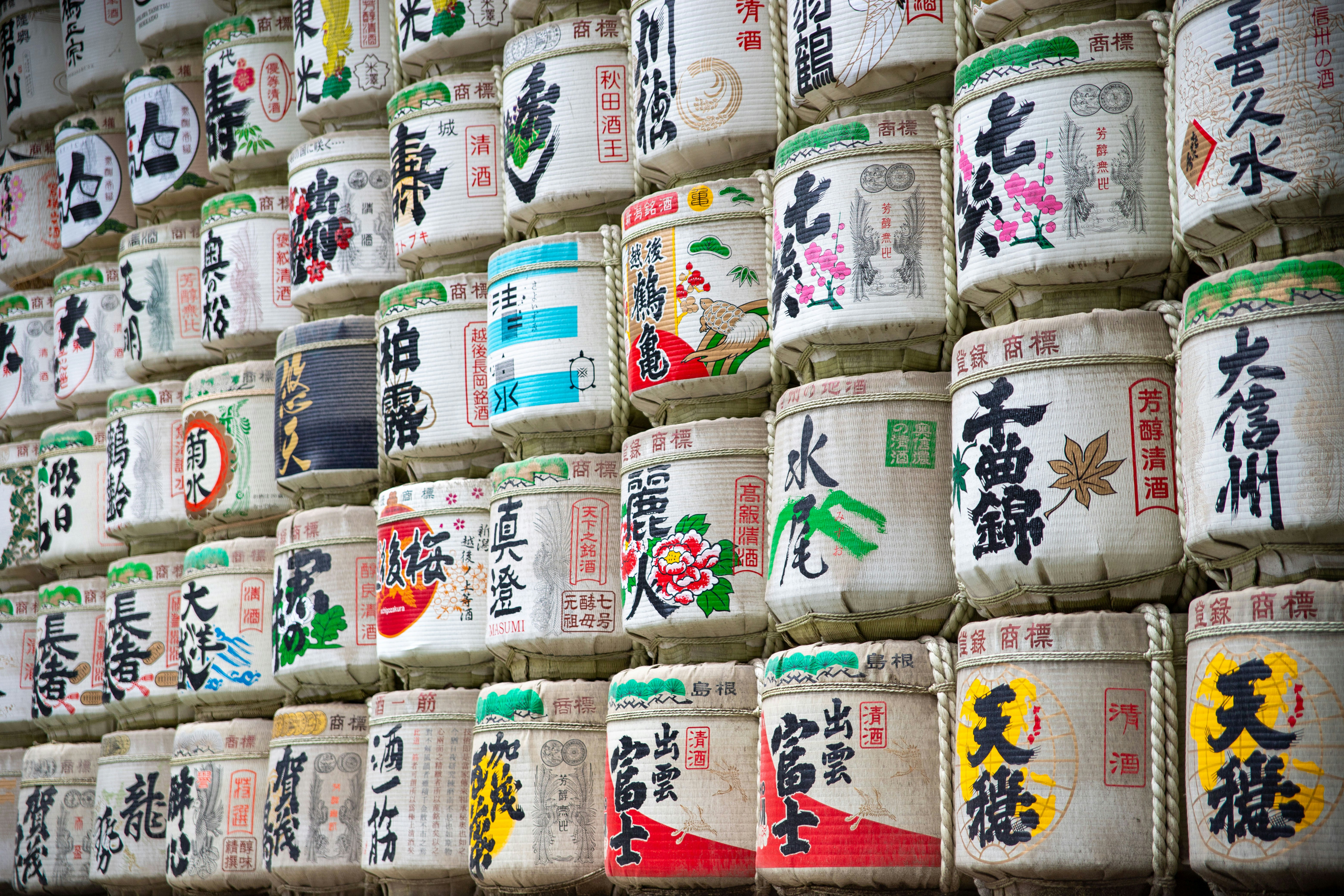 Wall of sake barrels with japanese writing and art.