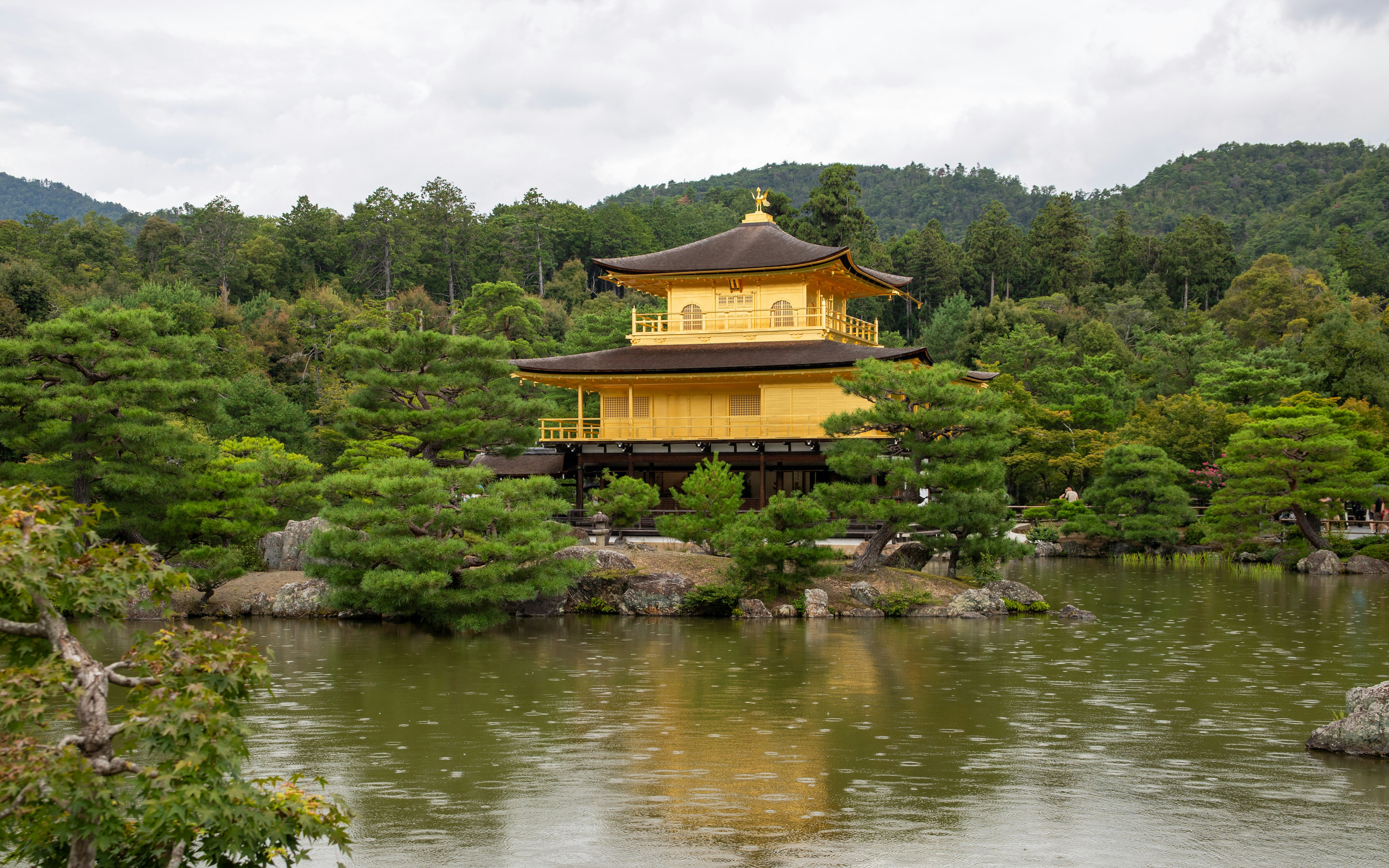 Golden pavilion temple surrounded by trees and water.