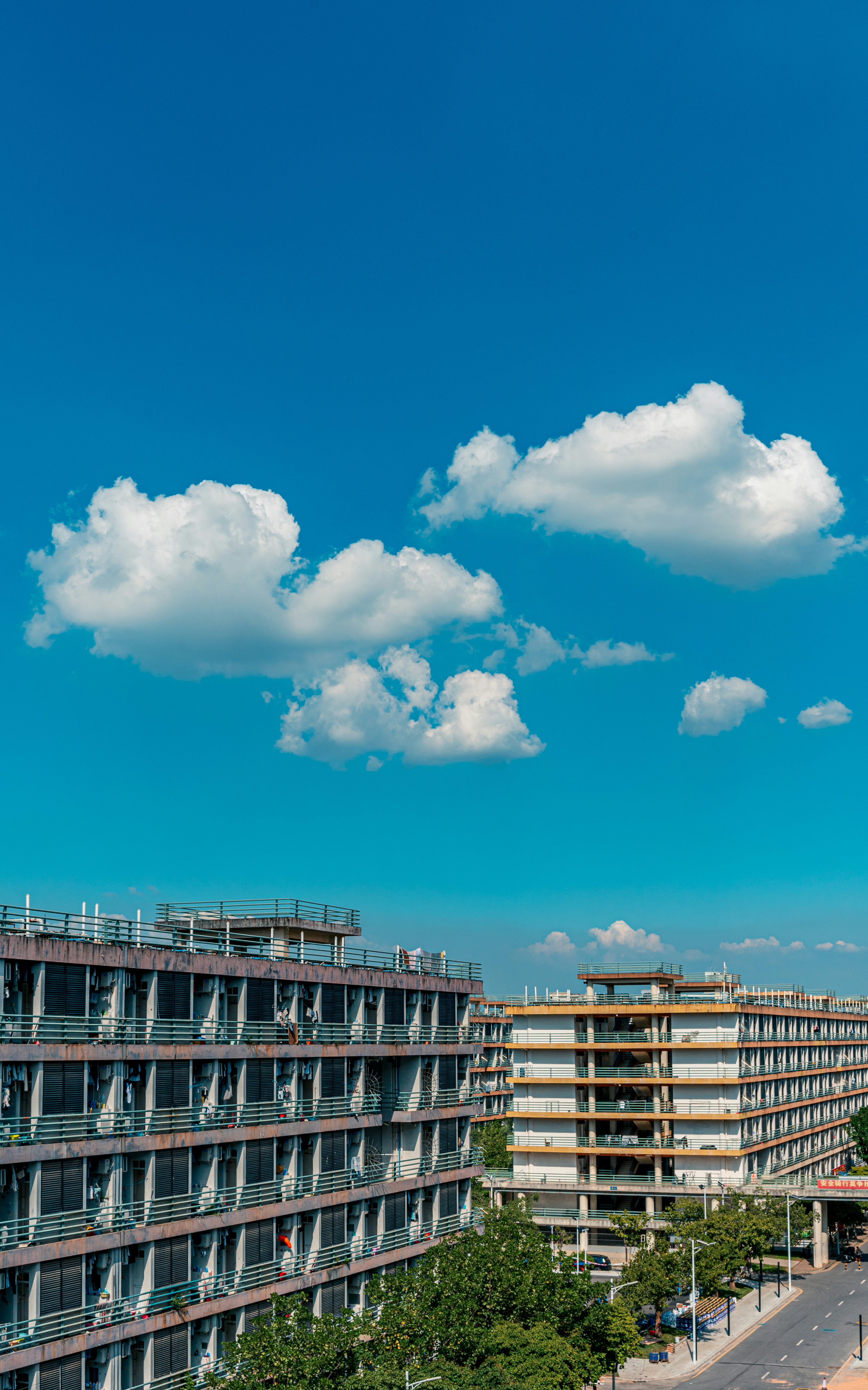 Two apartment buildings under a bright blue sky.