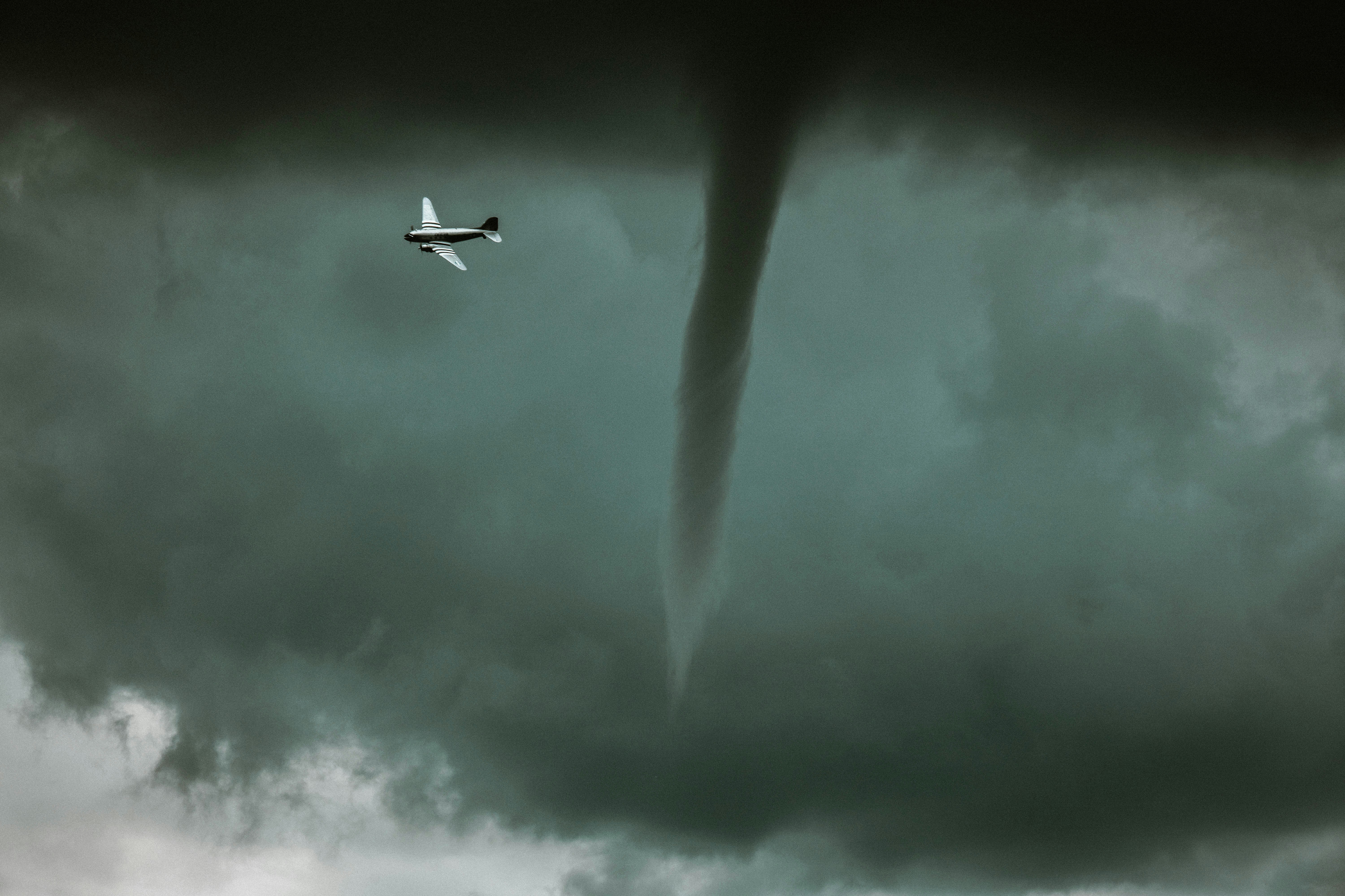 Small airplane flies near a powerful tornado.