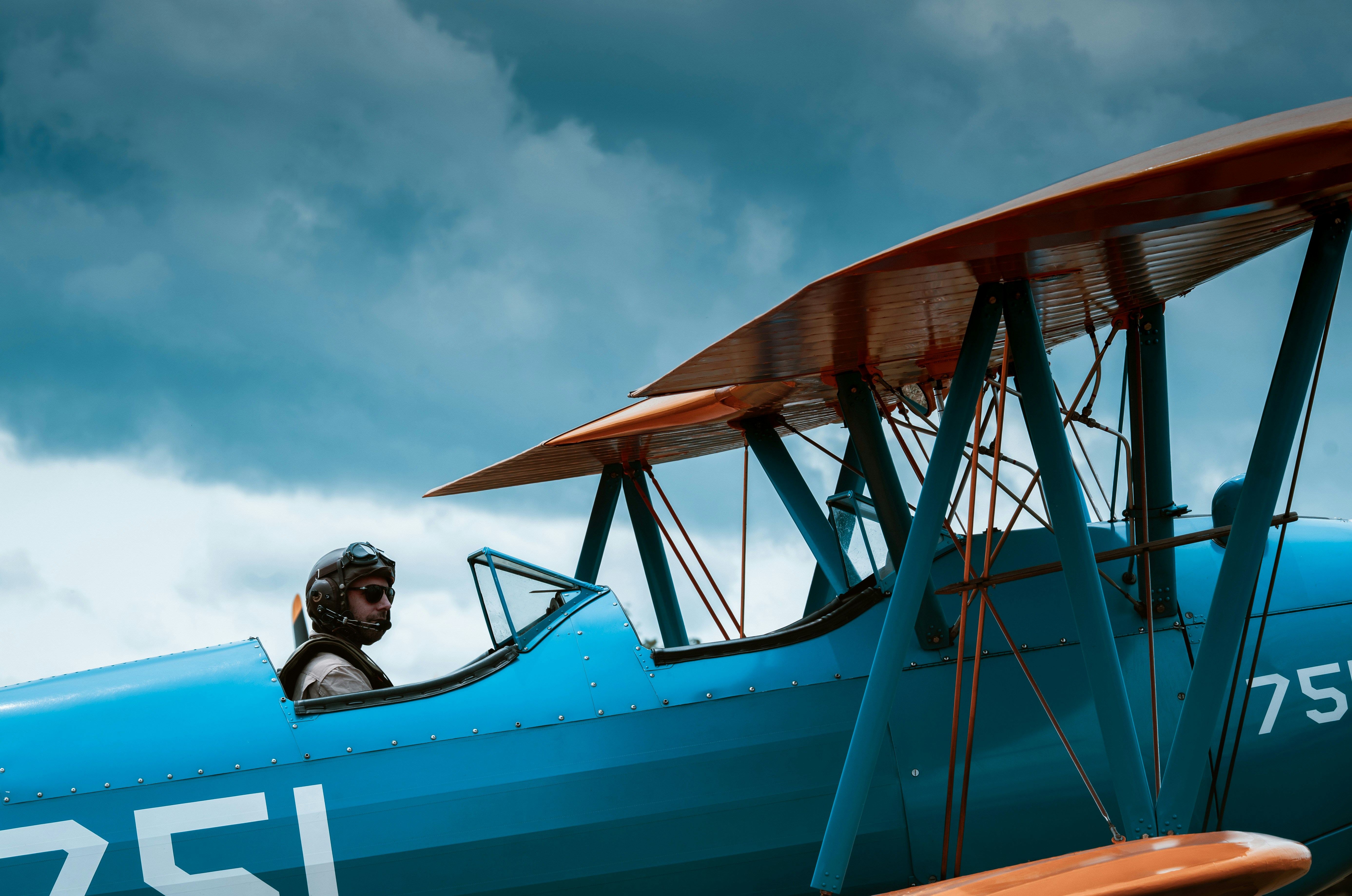 Pilot in einem Vintage-Doppeldecker unter bewölktem Himmel