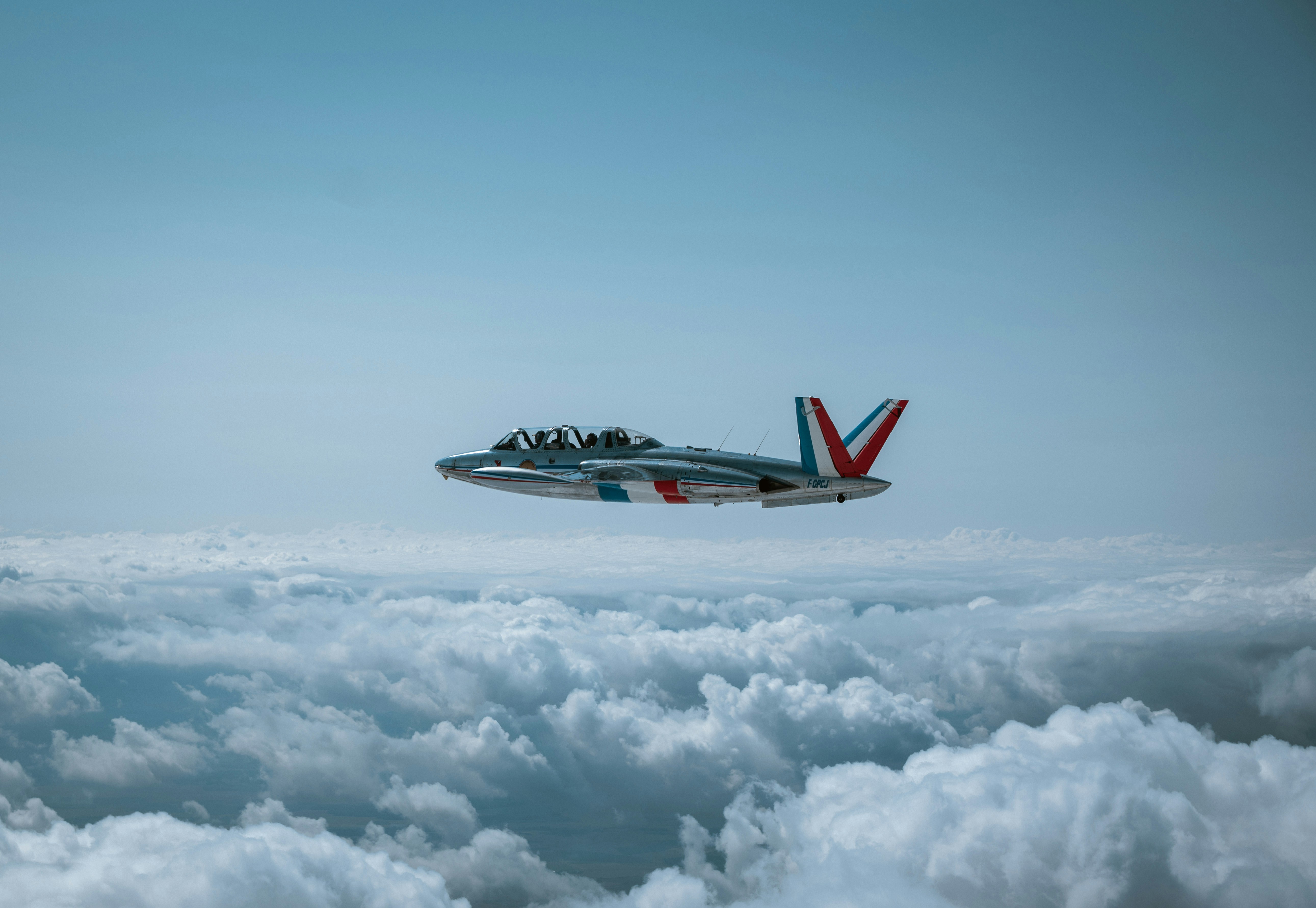Ein Düsenflugzeug fliegt über flauschige weiße Wolken.