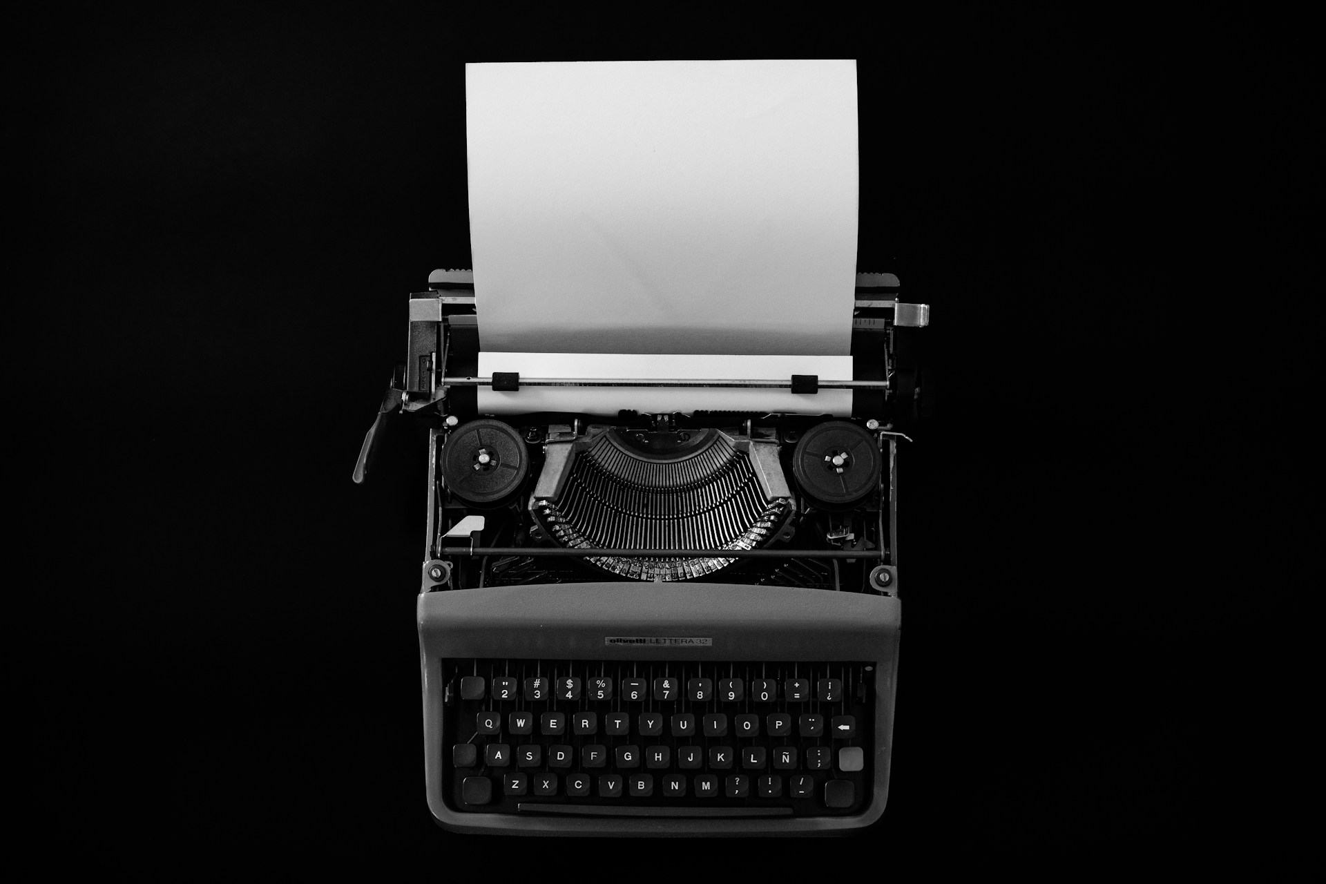 Vintage typewriter with blank paper on black background