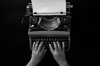 Hands typing on a vintage typewriter with paper.