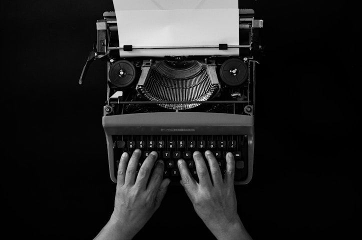 Hands typing on a vintage typewriter with paper.