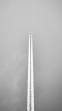 Airplane leaving a contrail against a gray sky